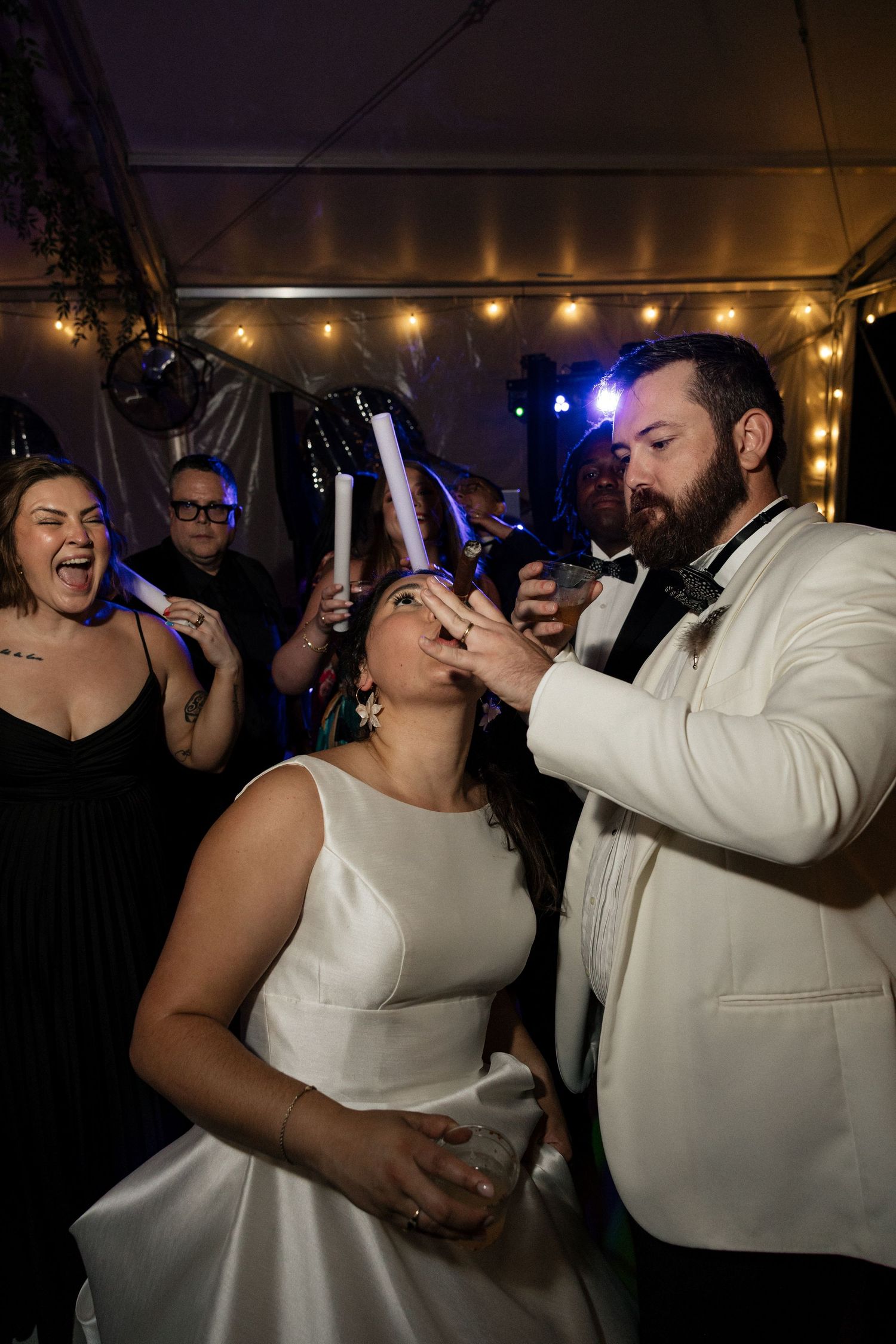 Bride and groom sharing a fun moment with glow sticks on the wedding reception dance floor.
