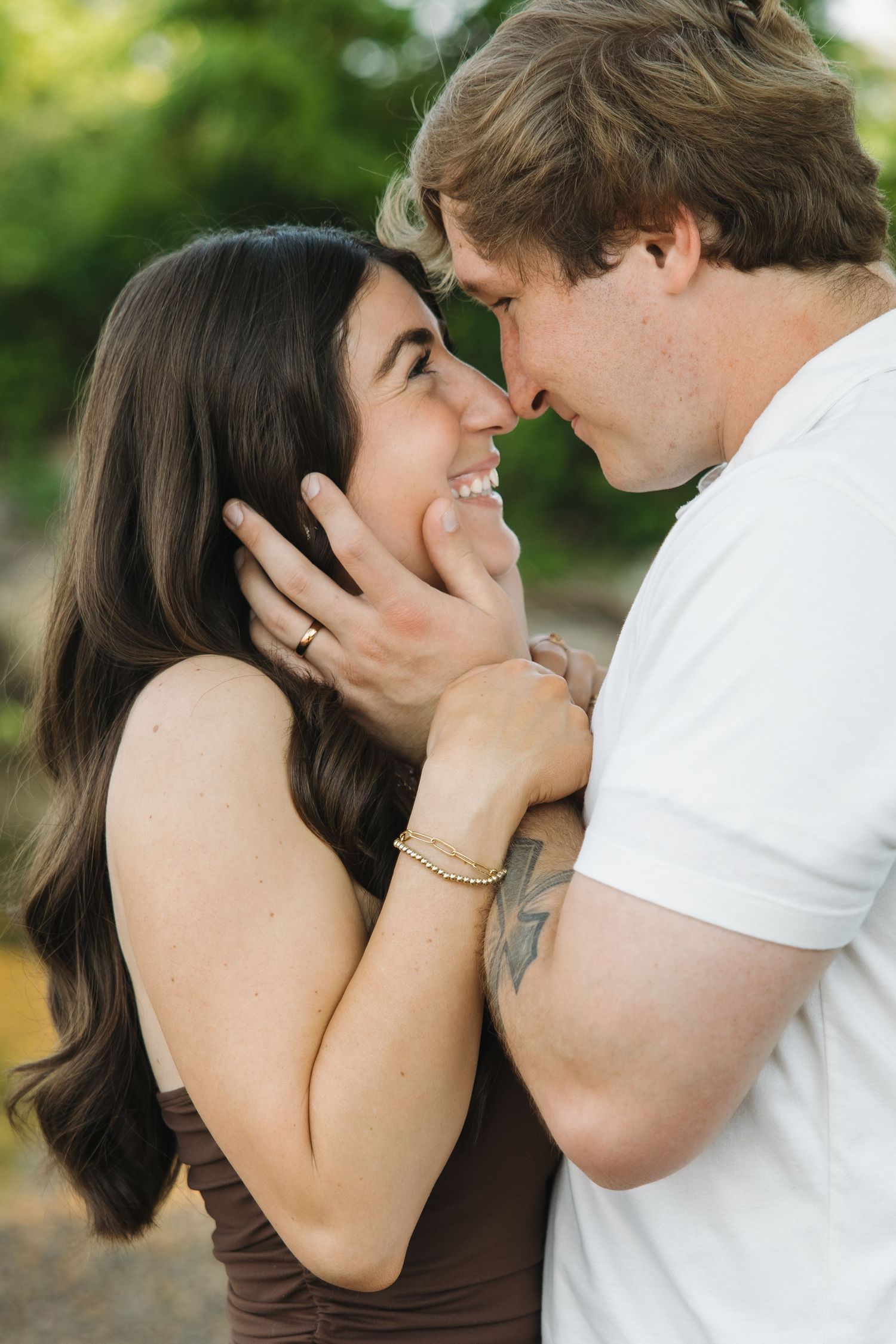 A smiling couple shares an intimate moment, nearly kissing, with the man gently cupping the womans face.