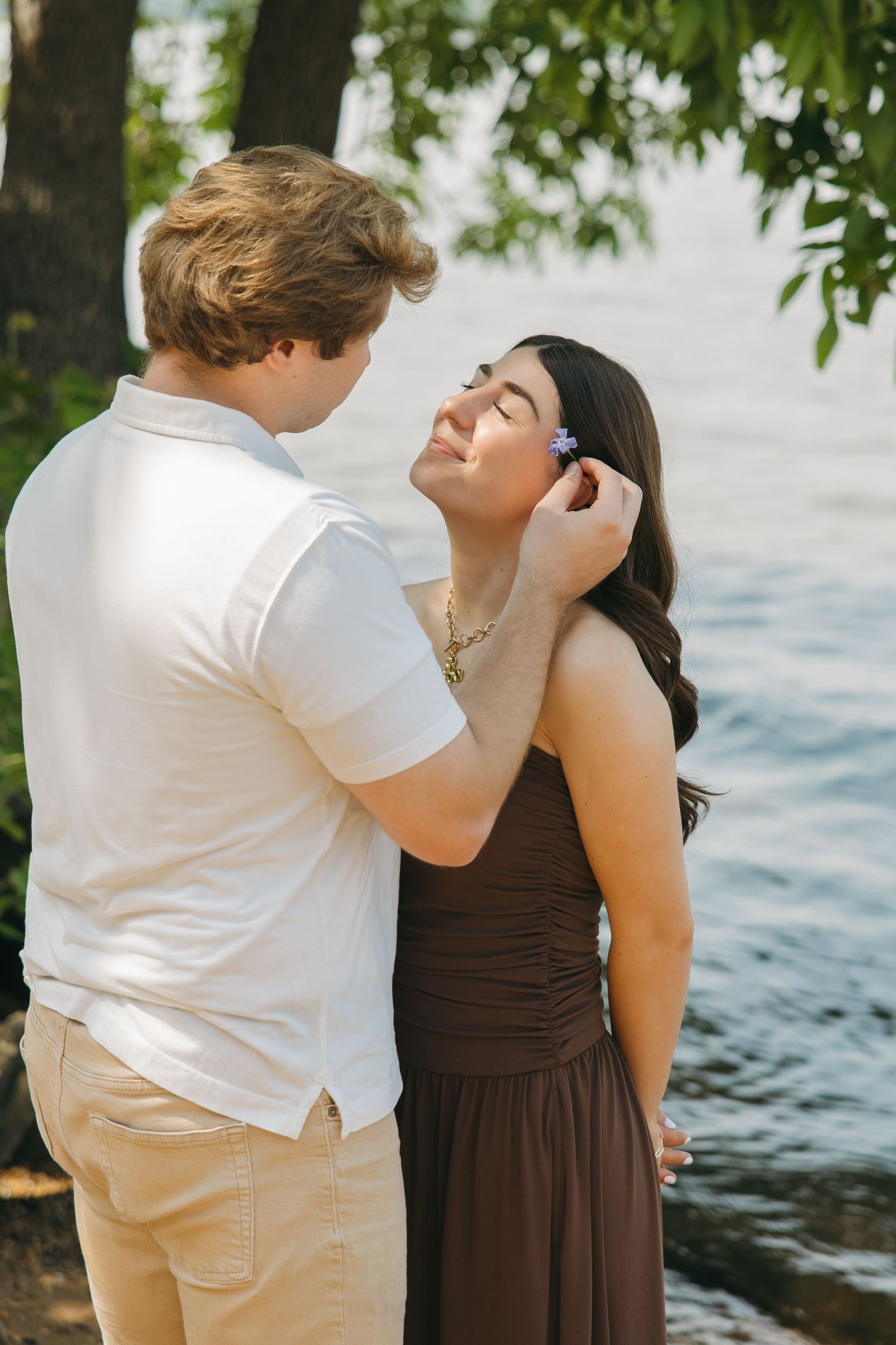 Romantic couple sharing a tender moment by the water's edge outdoors.