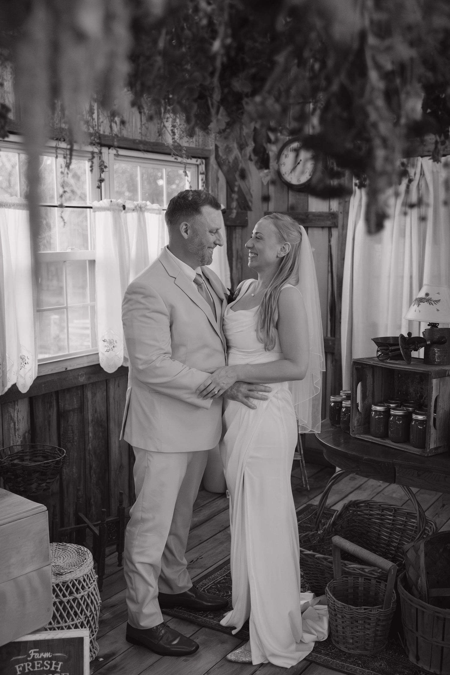 Bride and groom sharing a joyful embrace inside a charming rustic cottage, black and white photo.