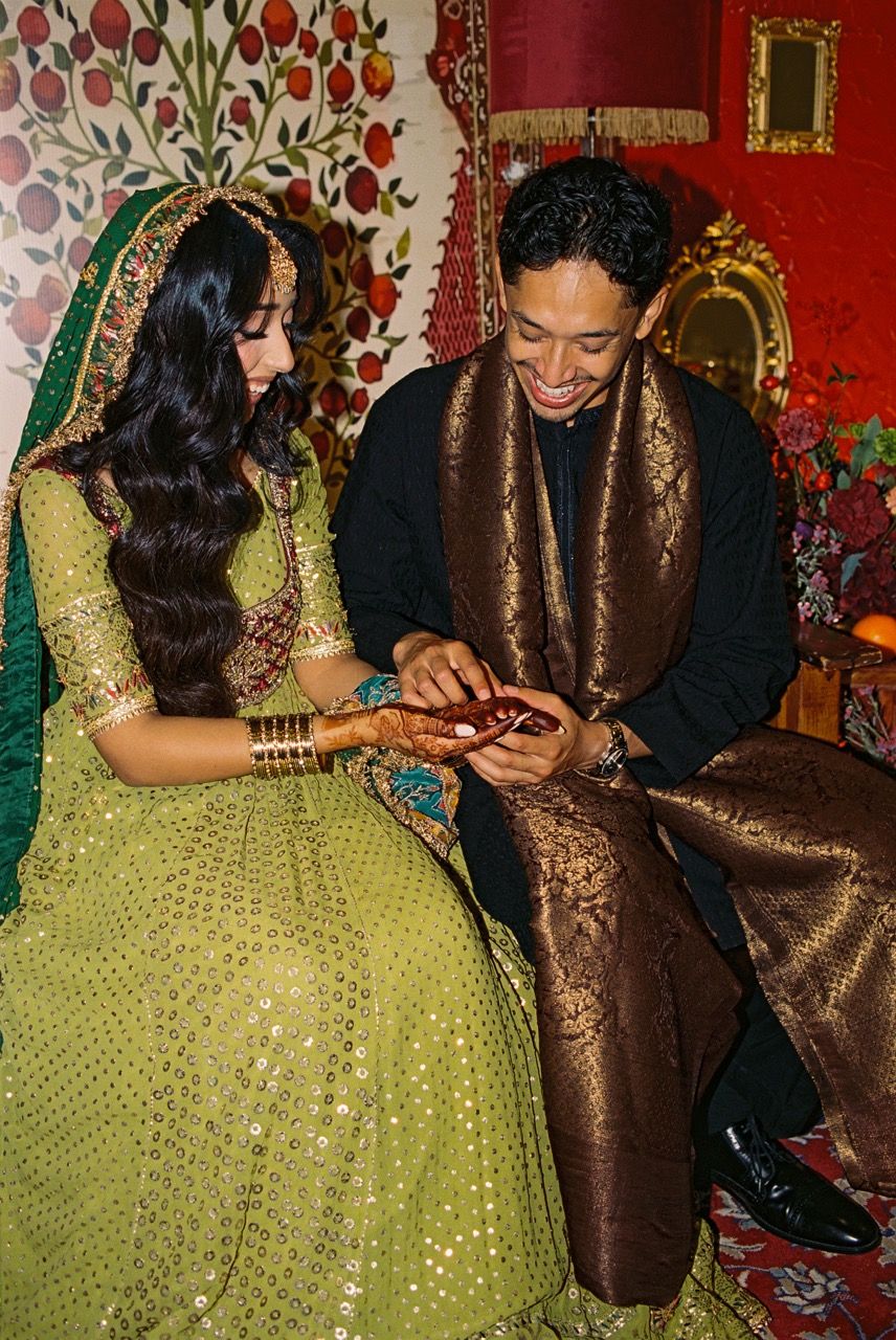 Bride and groom sitting and admiring the bride's henna on their mehndi day.