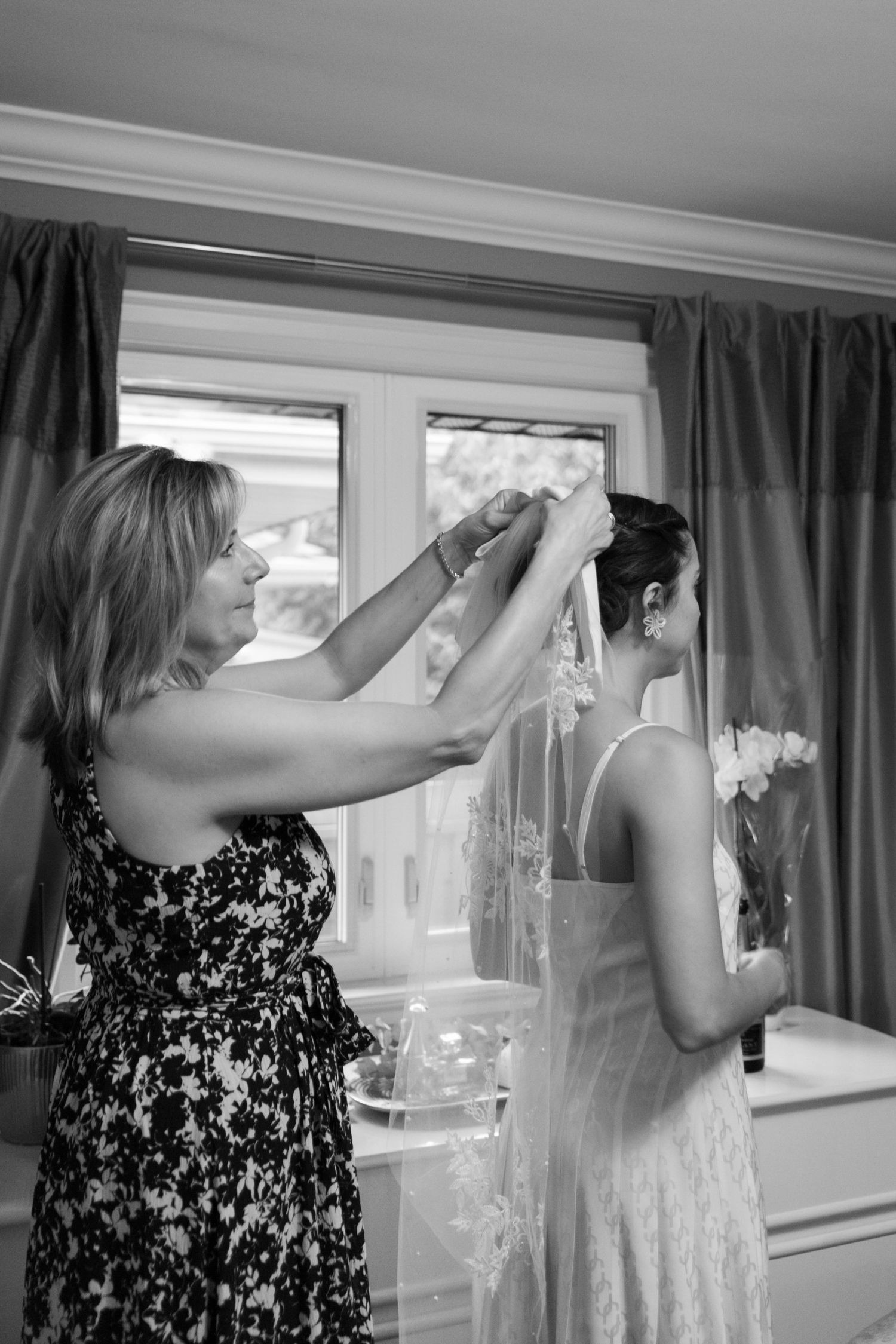 Bride getting ready on her wedding day with the help of her mother. Captured in black and white.