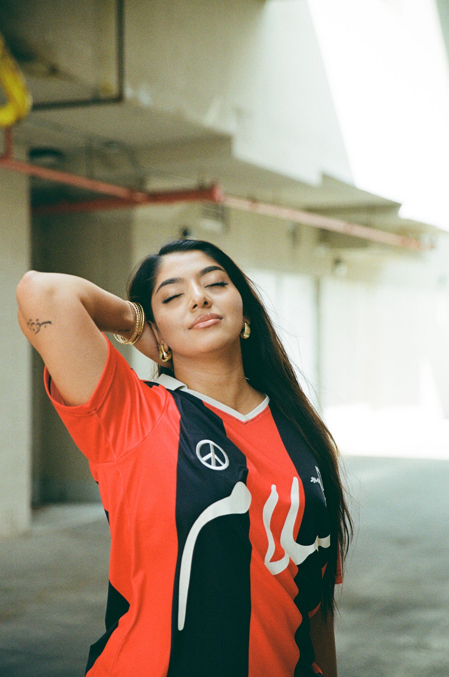 Film portrait of woman with one arm up and a smirk..