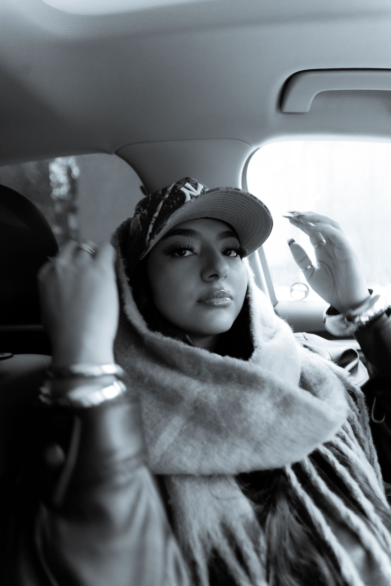 Woman wearing a hat and scarf in black and white.