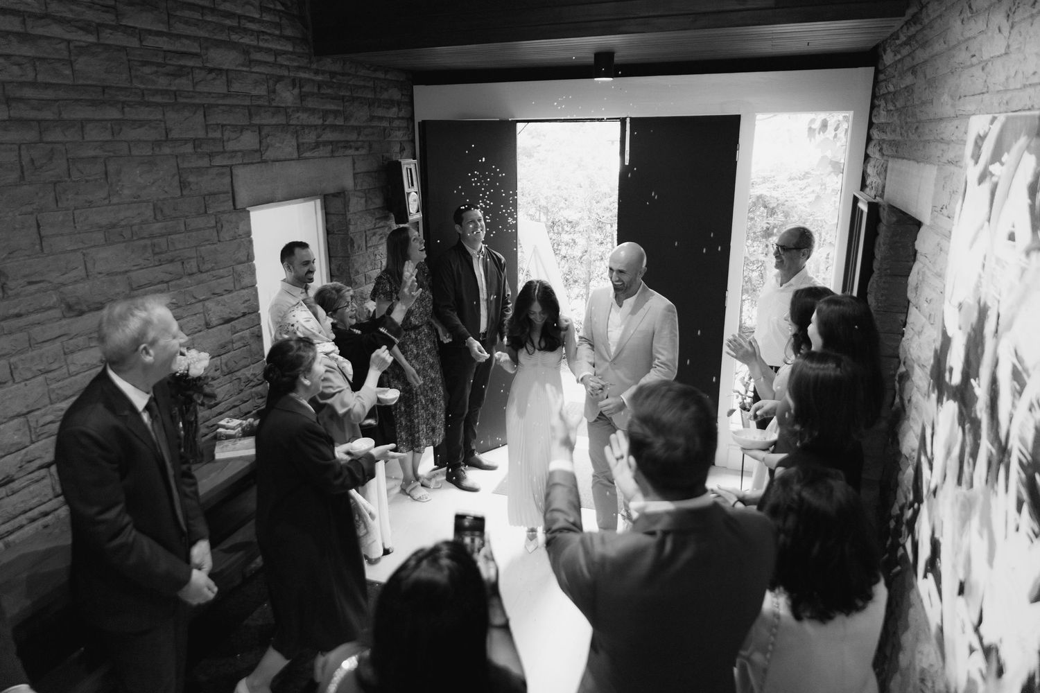 Fiancés walk in to their engagement party together to a room full of their family and friends. Guests throw sugar in the air.