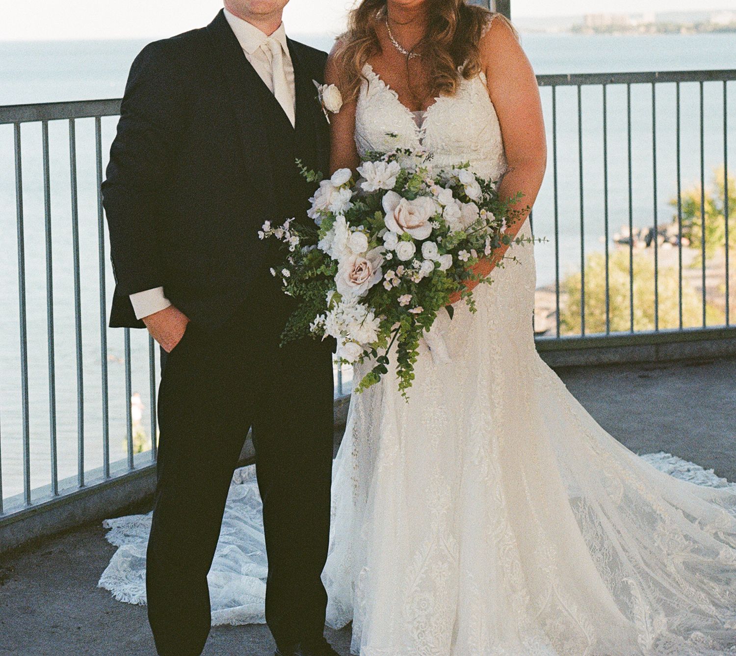 Film photo of bride and groom's outfits. The bride holds a lush bouquet of florals and greenery.