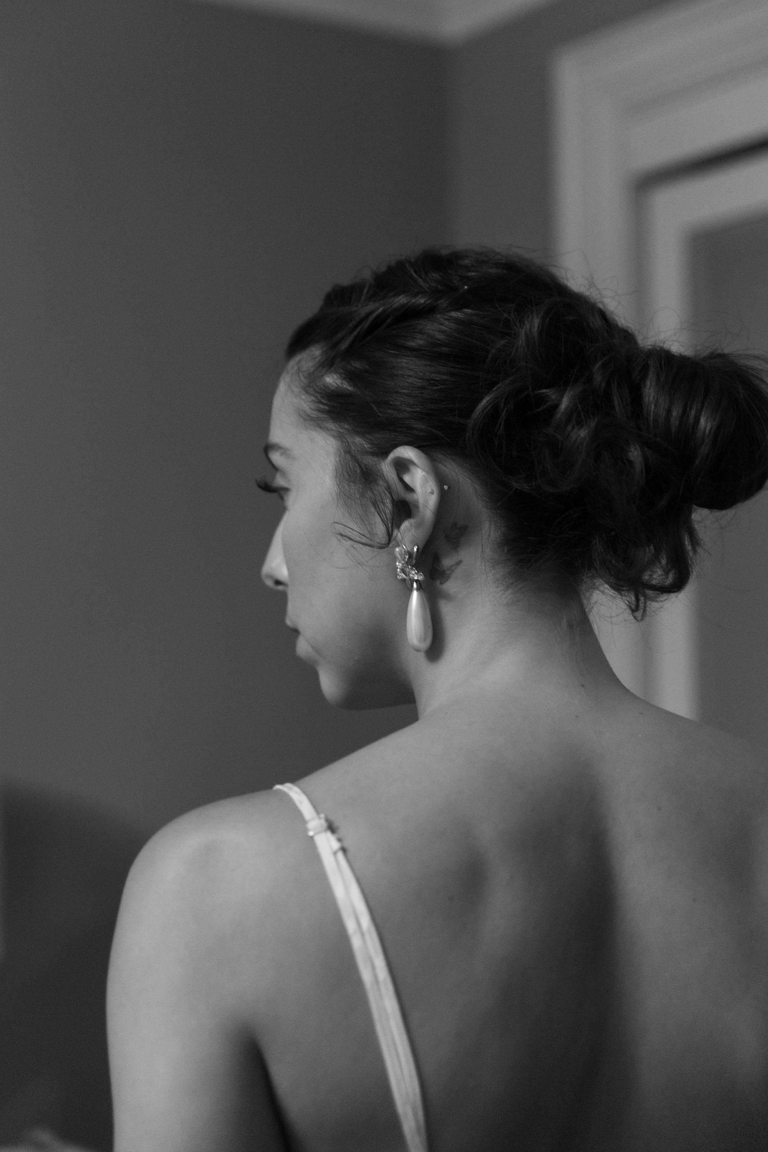 Bride looking over her left shoulder wearing a dangling pearl earing.