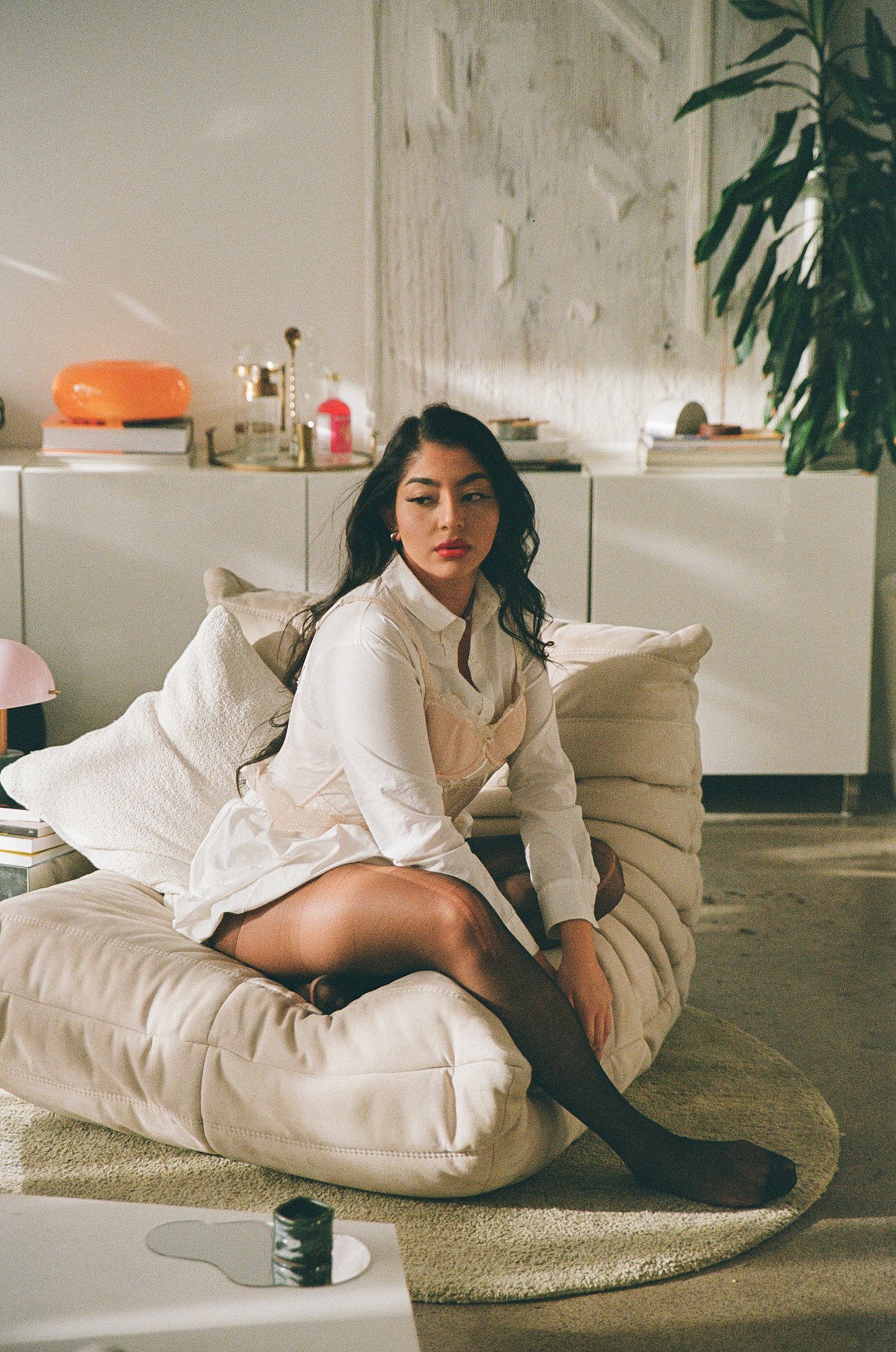 Woman sitting on beige lounge chair looking into the distance.
