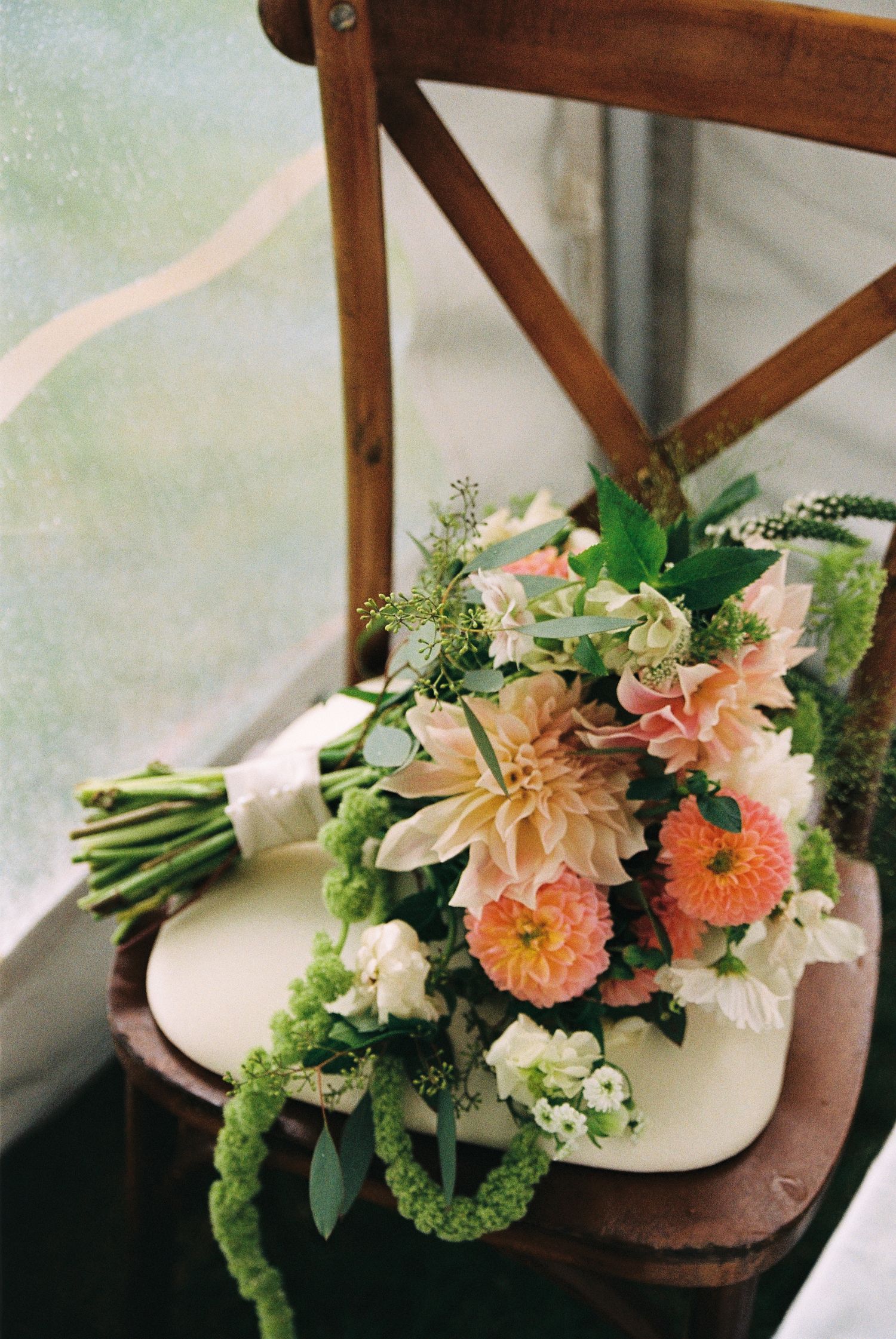 Bridal bouquet filled with white, orange, light pink, and green florals captured on 35mm film.