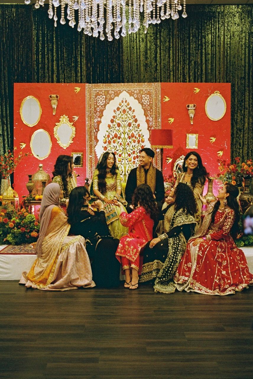 Bride, groom, and the bridal party all seated together on stage laughing and smiling together.