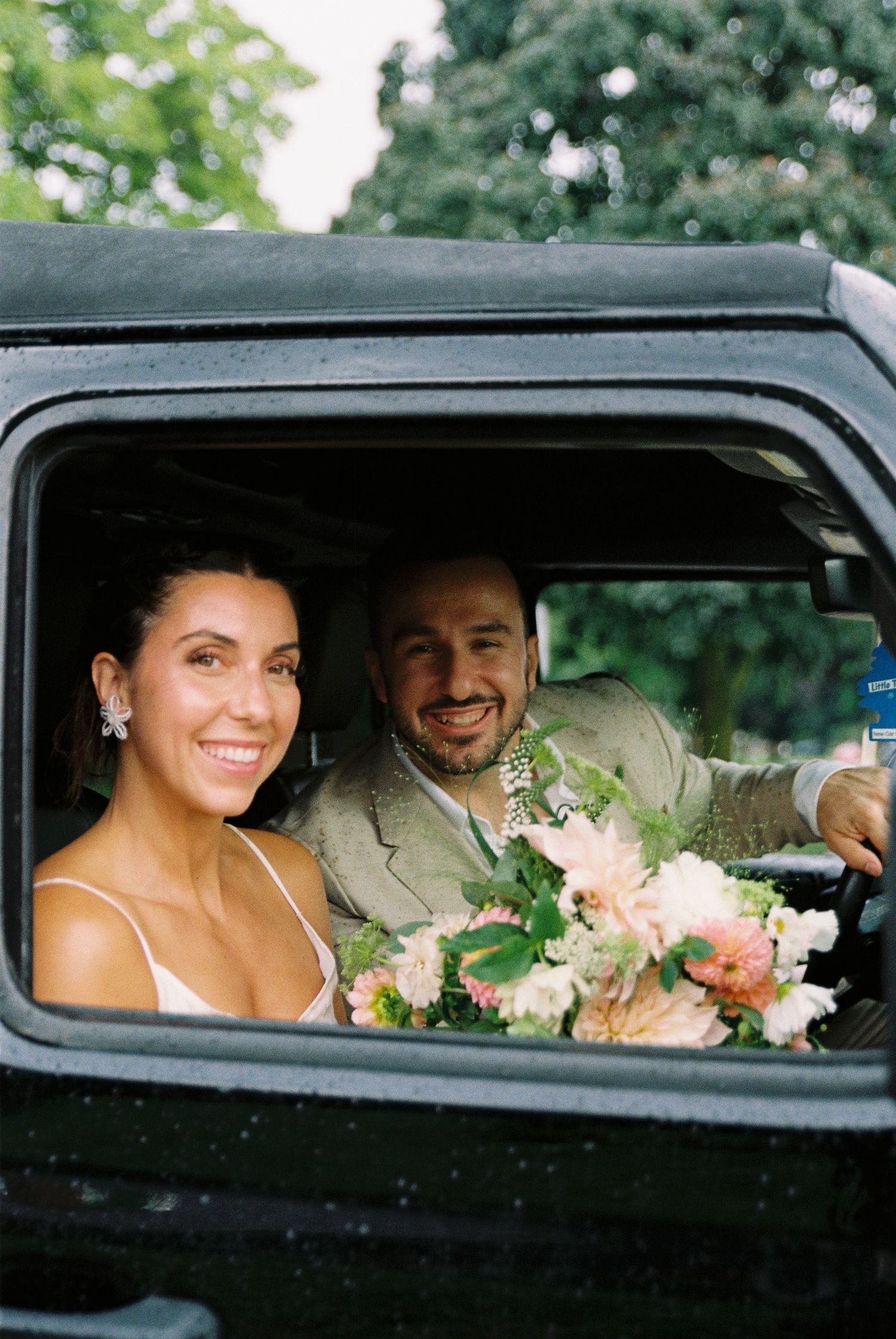 Bride and groom smiling inside of a car after being married.
