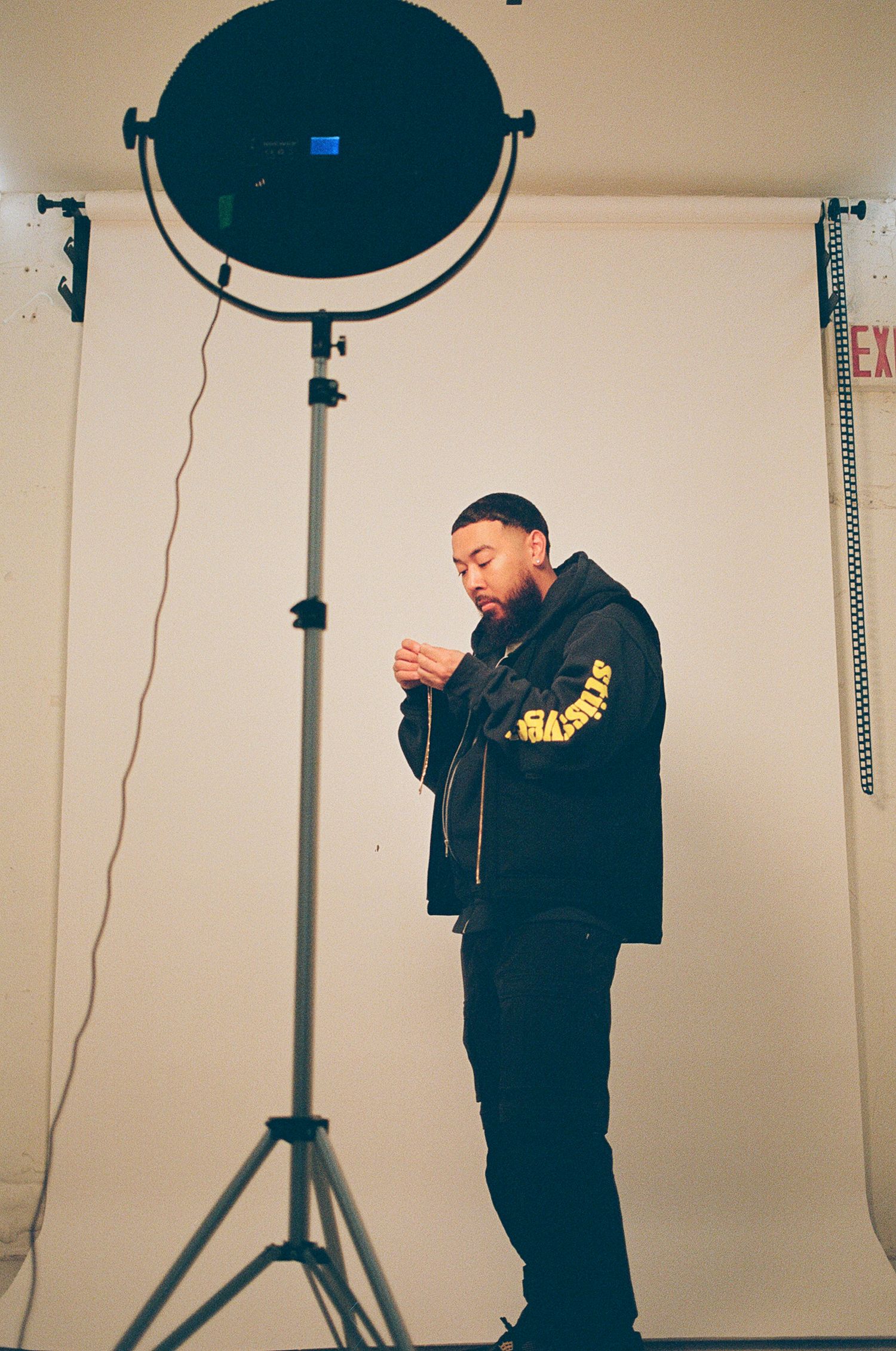Film portrait of man behind the scenes on set standing in front of a white background.