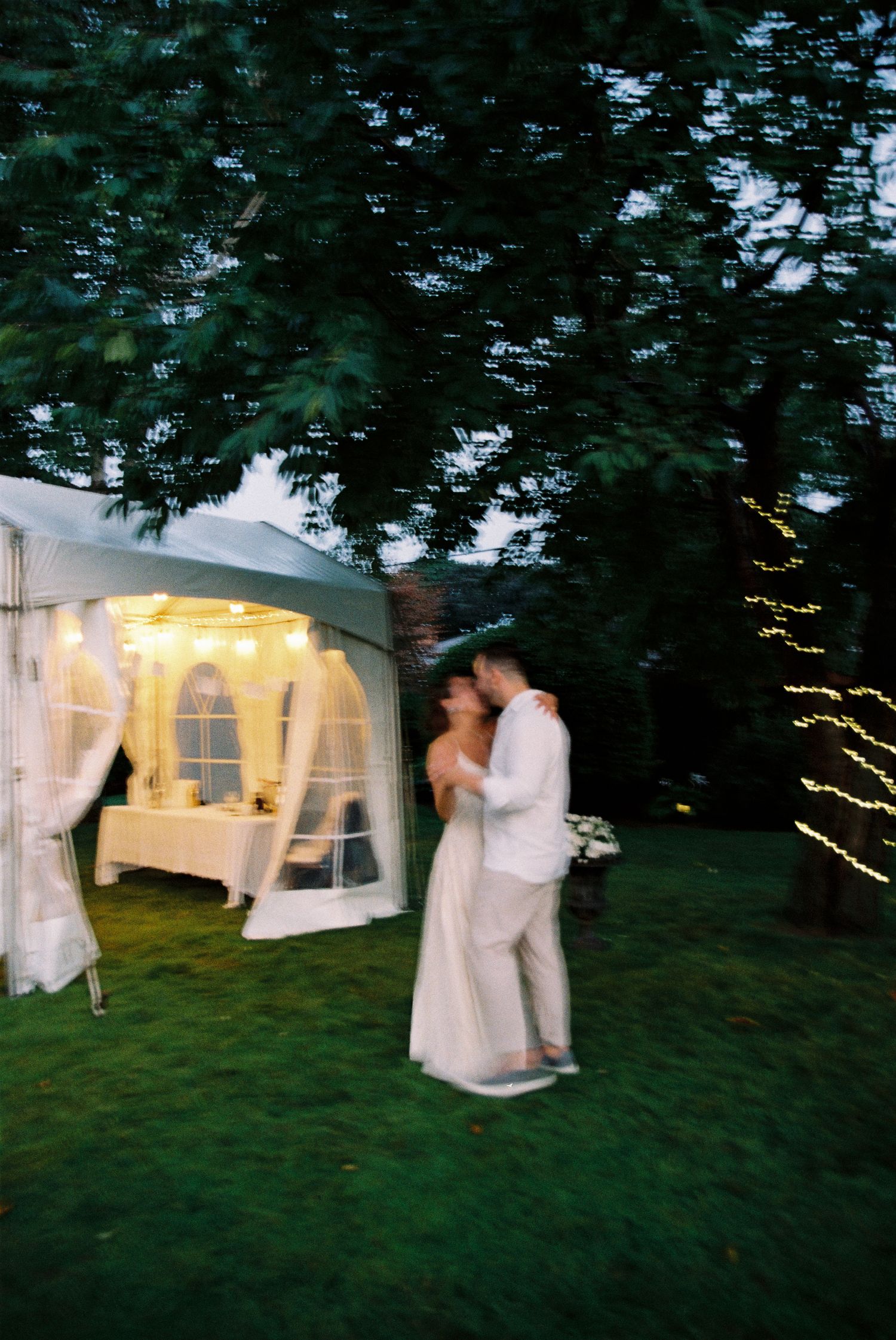 Bride and groom dance together under a cherry tree after their backyard elopement ceremony.