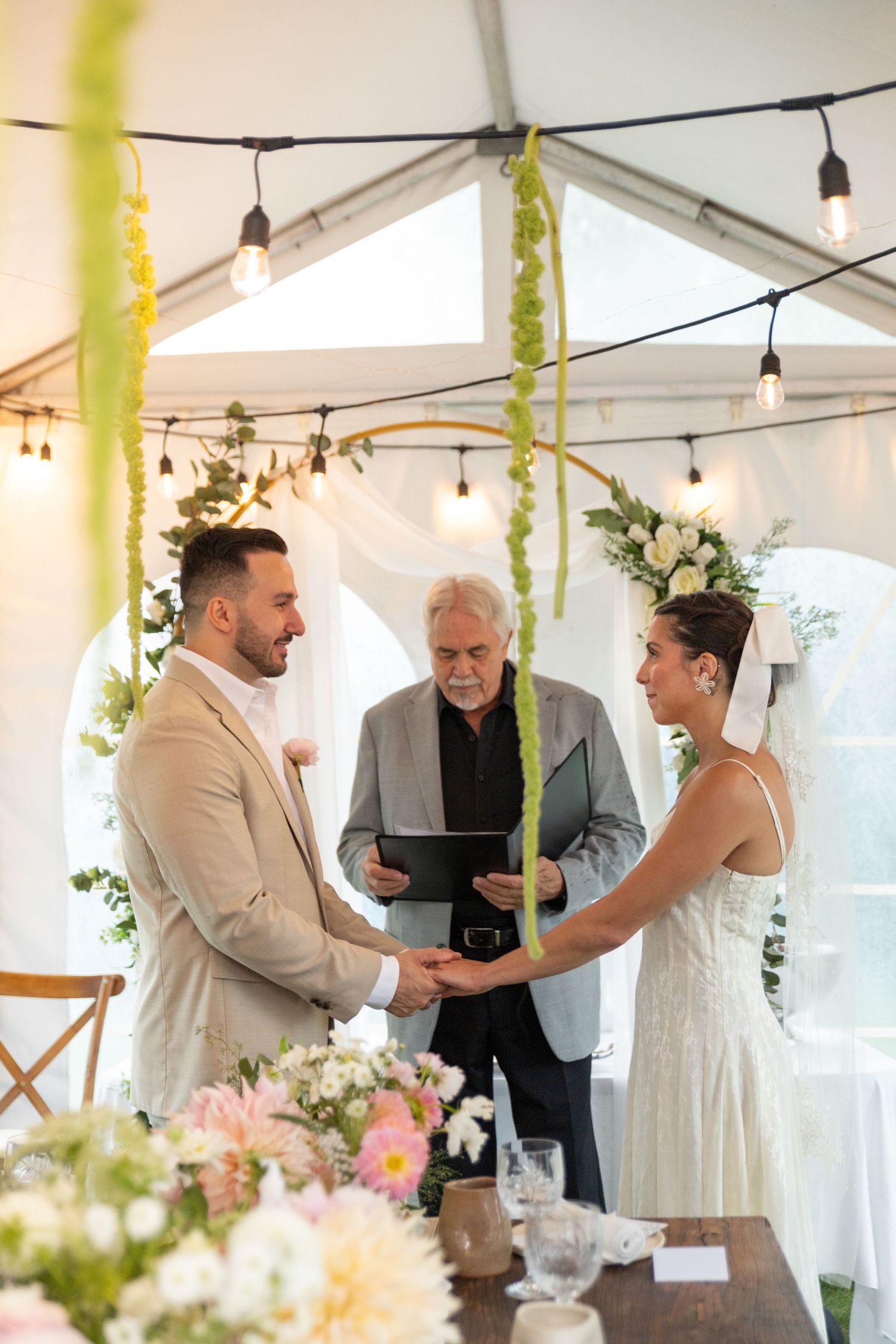 Bride and groom in backyard elopement ceremony holding hands in front of the altar.