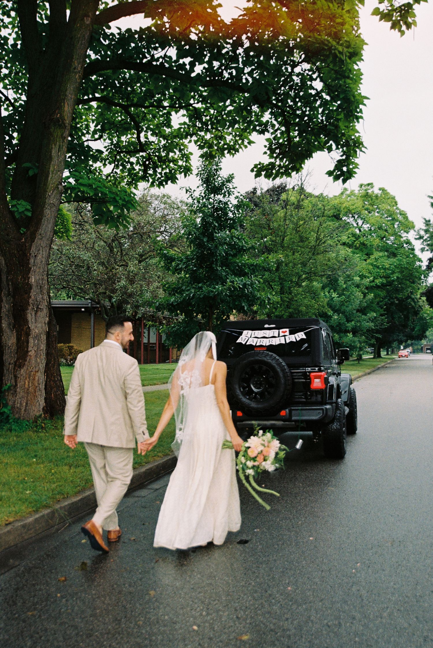 Bride and groom walking towards their jeep that reads 