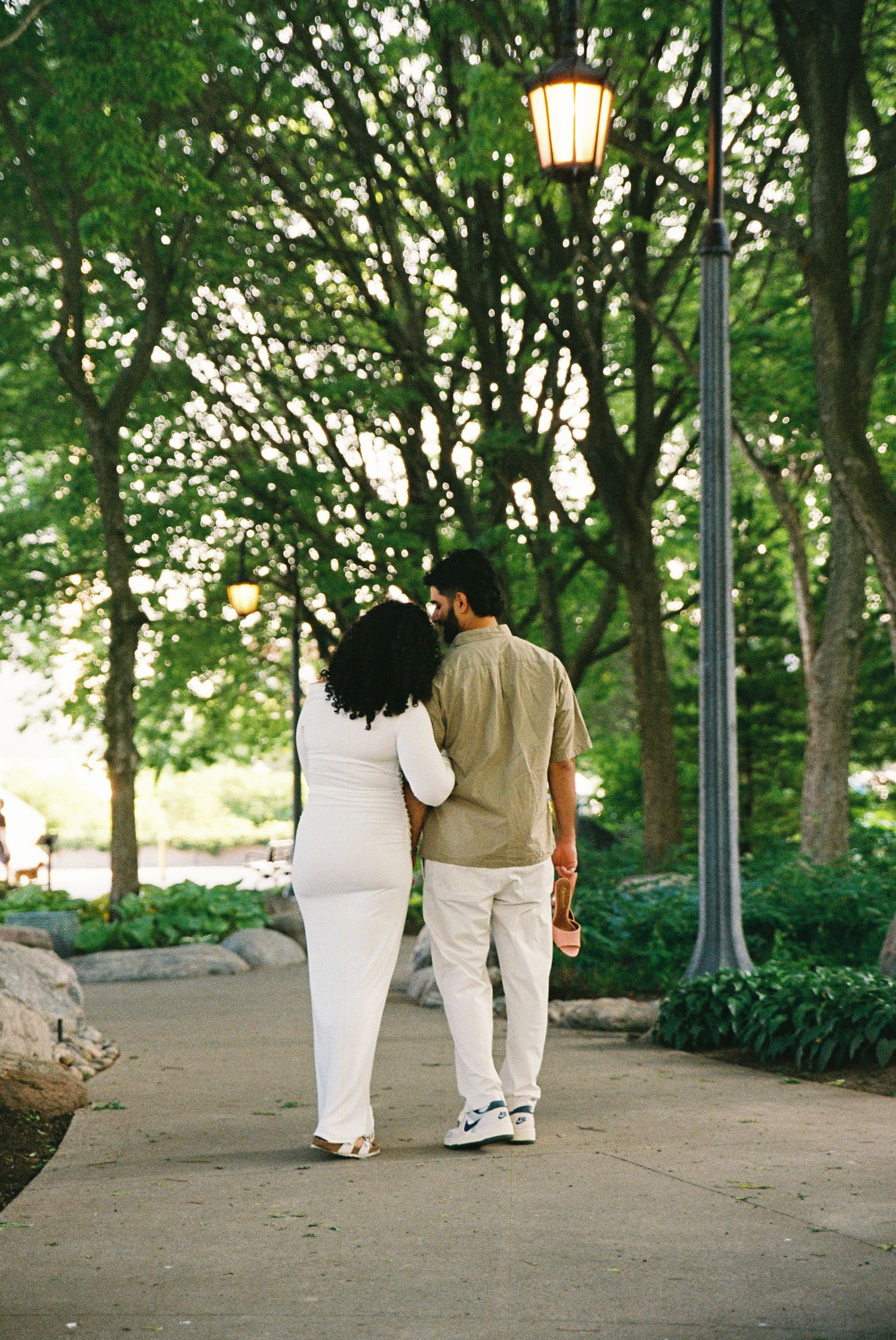 A couple walking in the Toronto Music Gardens together. The wife is resting her head on her husbands shoulder.