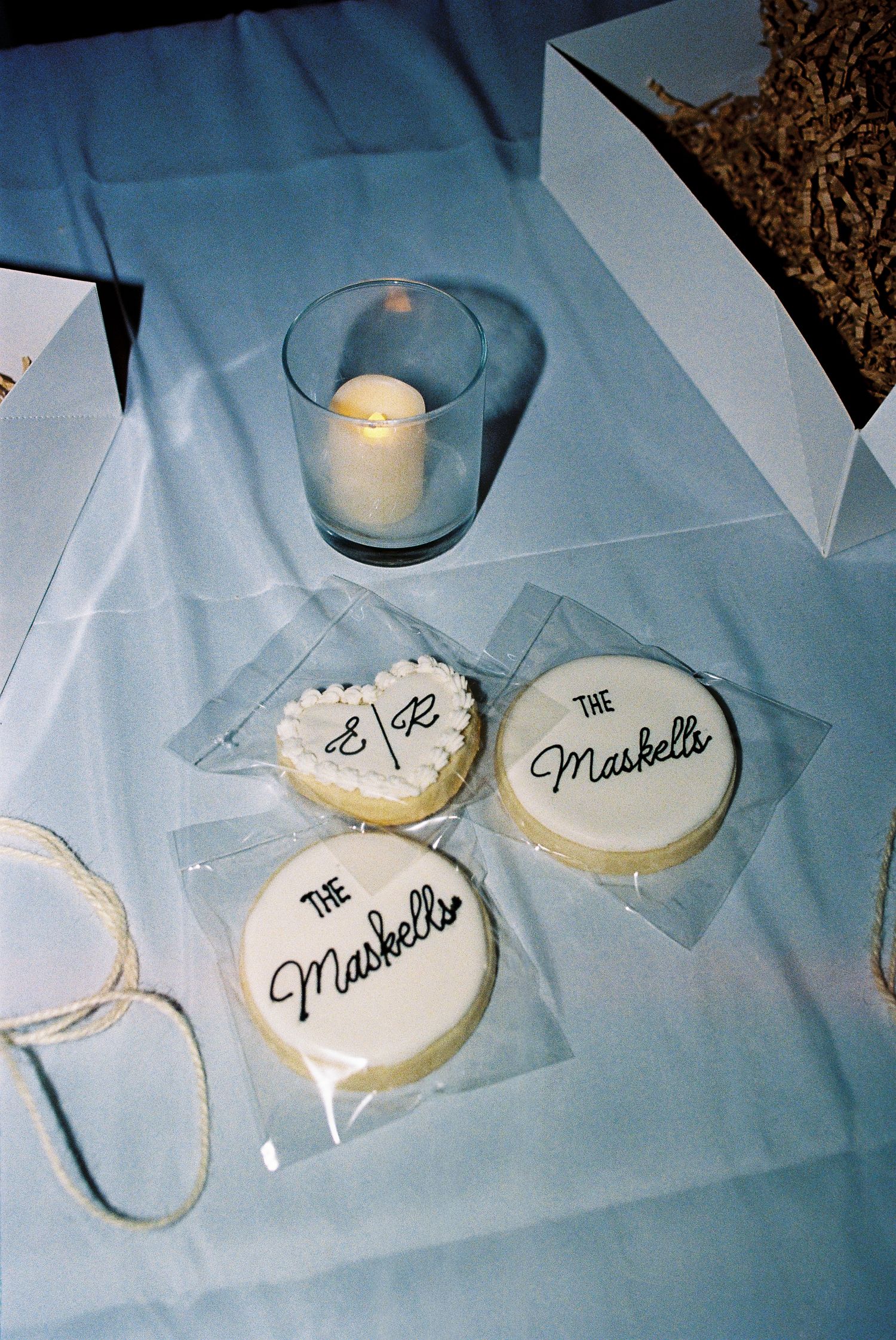 Wedding guest take-home gifts: white sugar cookies with black cursive font of their last name on top. Captured on 35mm film.