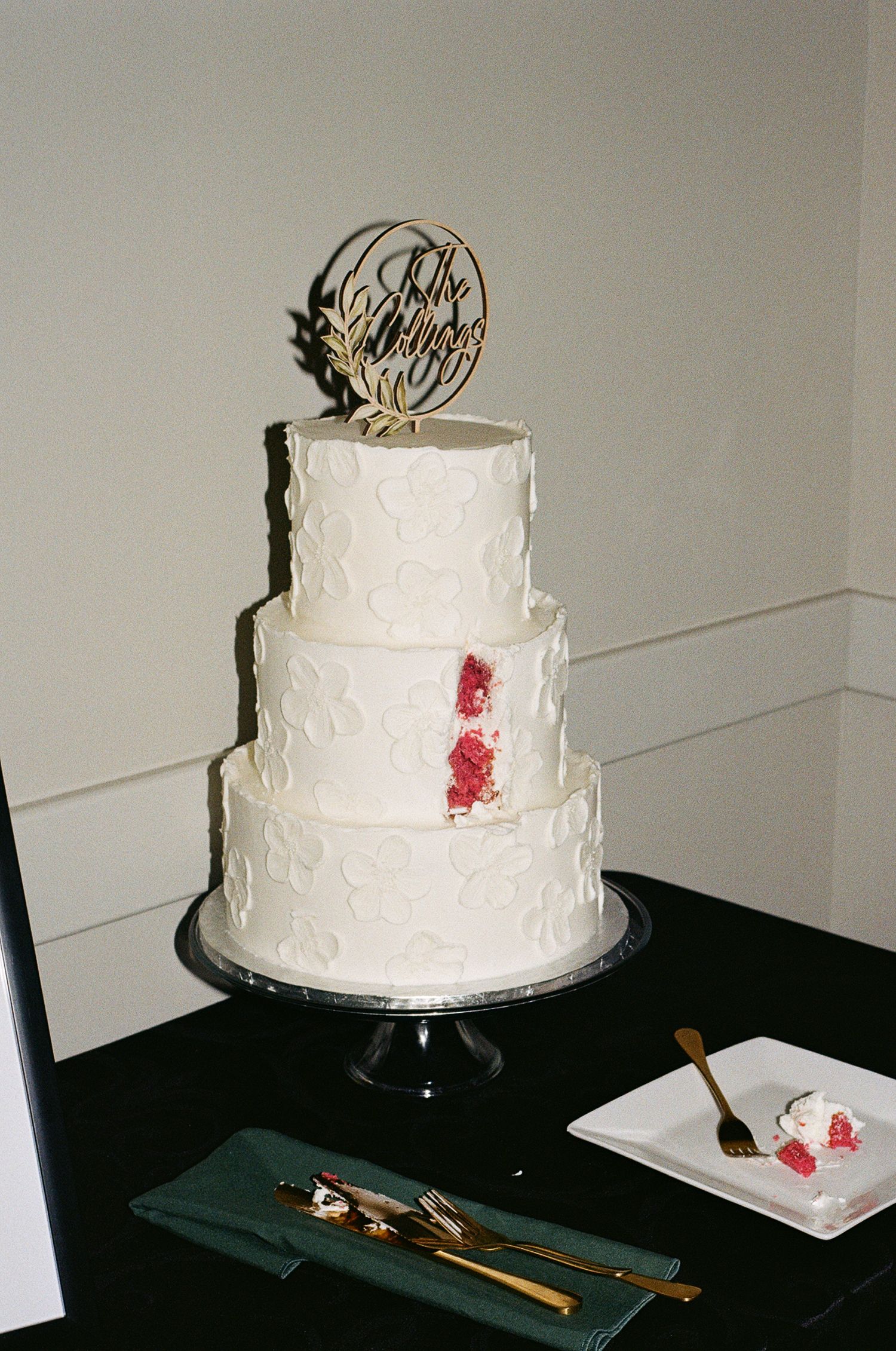 Film photo of three tiered white wedding cake with red velvet interior.