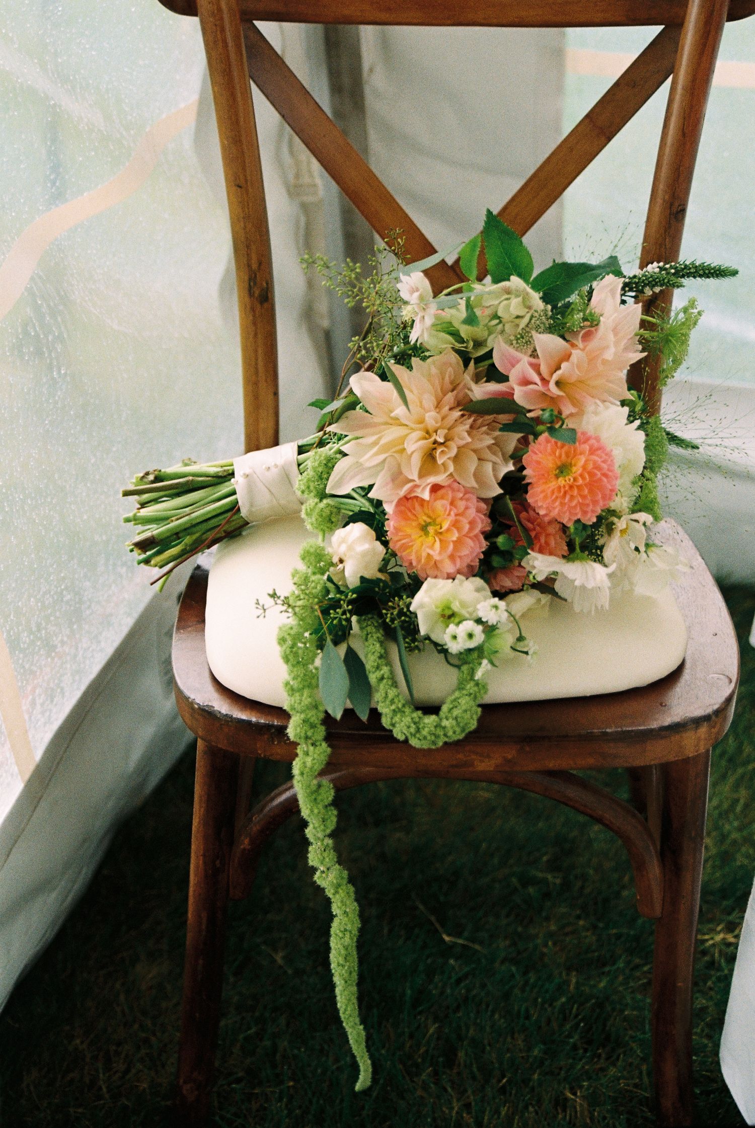 Bridal bouquet filled with white, orange, light pink, and green florals captured on 35mm film.