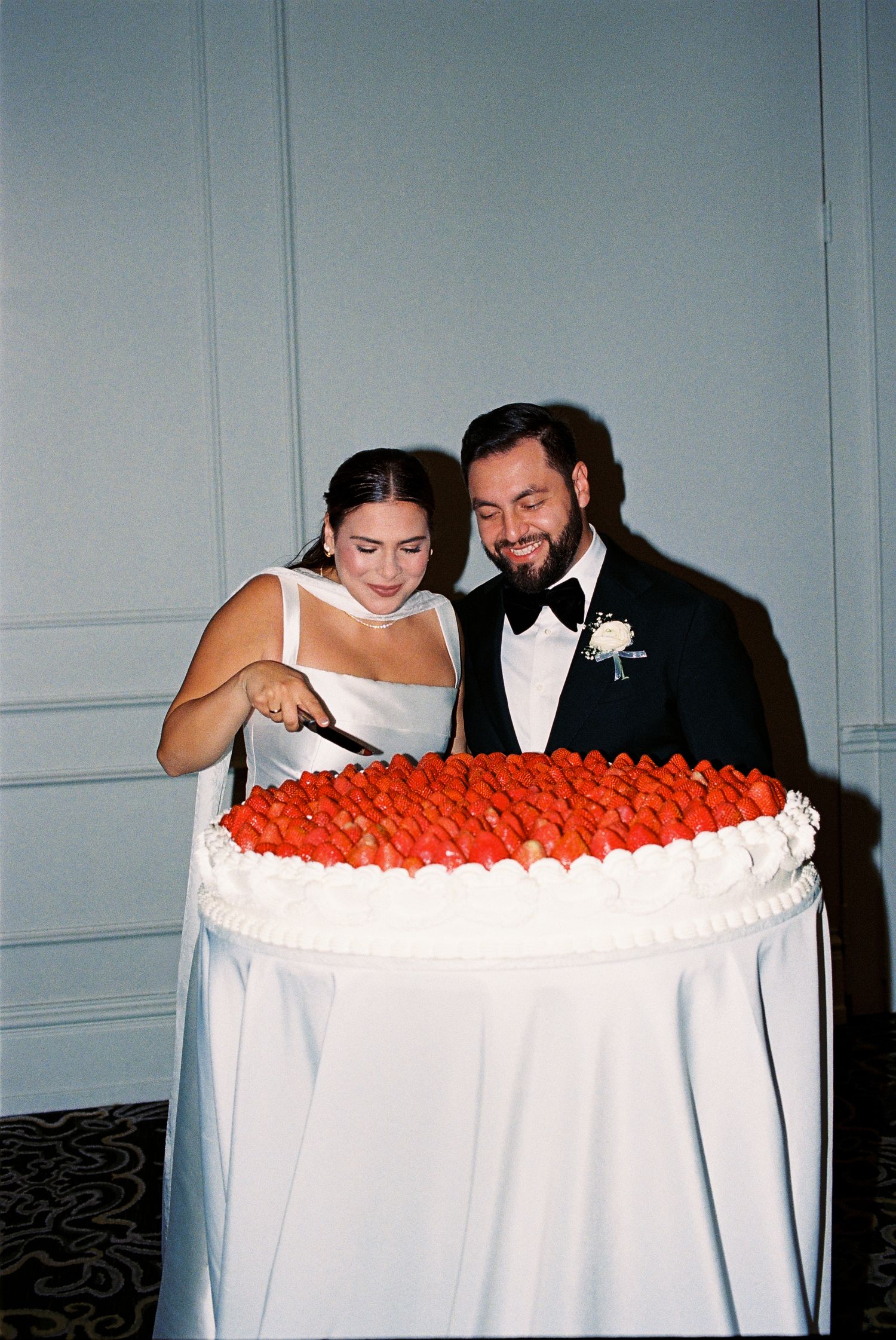 Bride and groom cut the first slice of their strawberry wedding cake.
