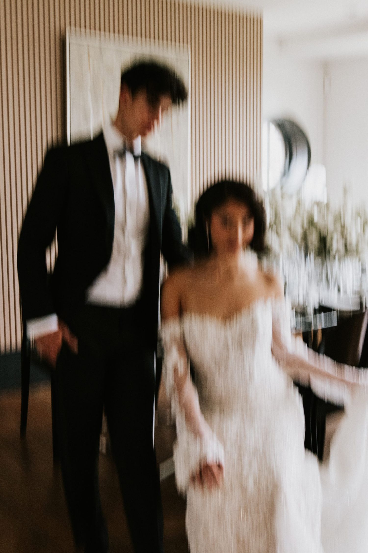 Motion blur captures a couple dancing together at their wedding reception in formal attire.