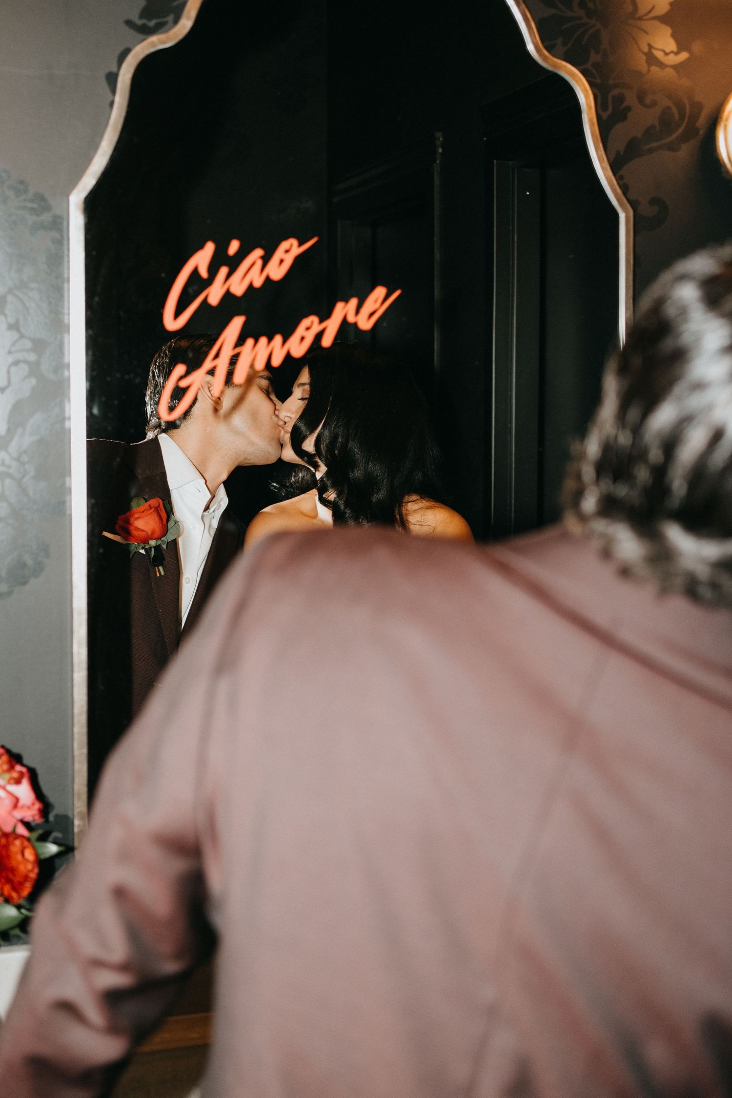 Silhouetted figures dance in front of a neon sign at a dimly lit venue.