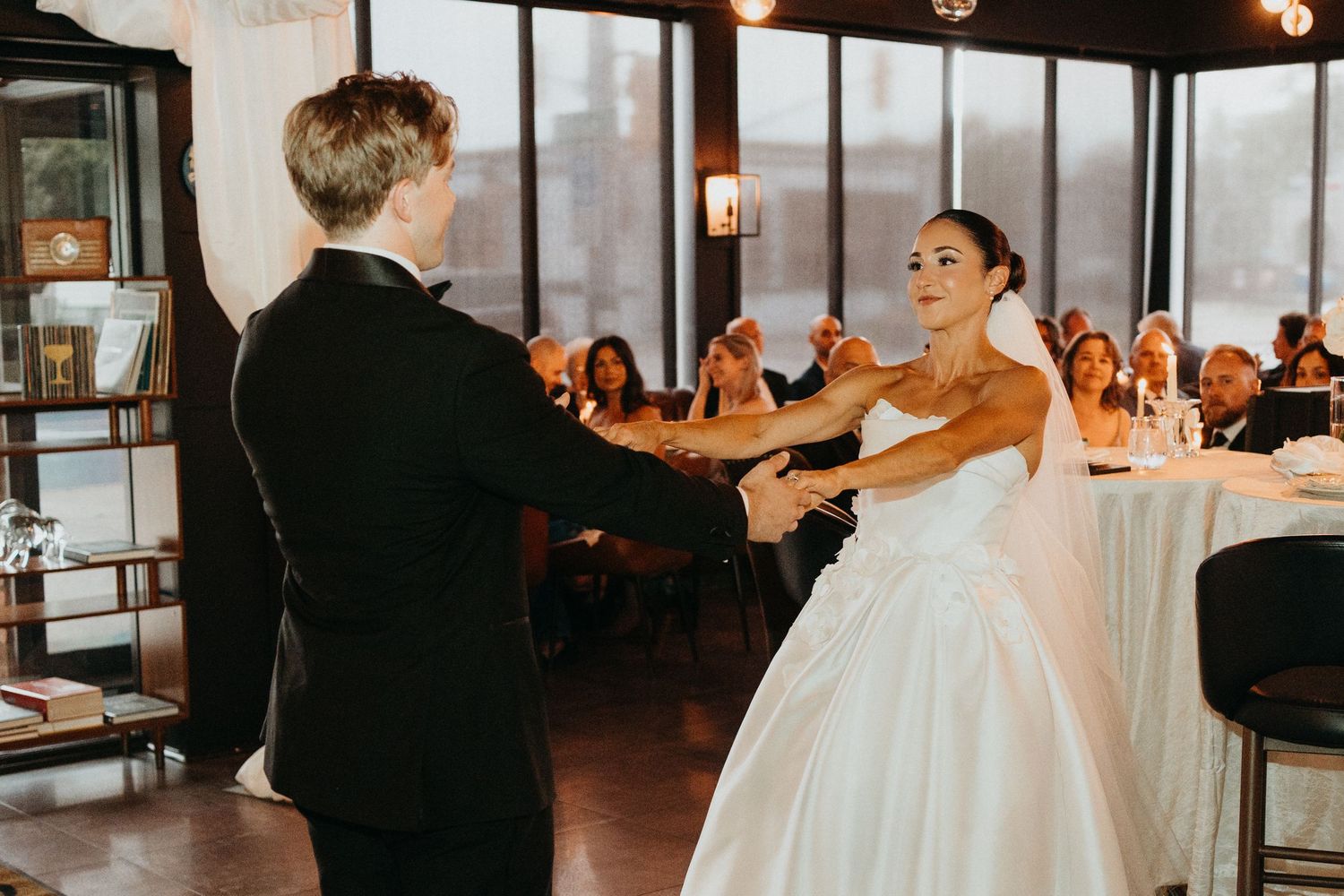 Wedding reception venue with elegant lighting and guests dancing in formal attire.