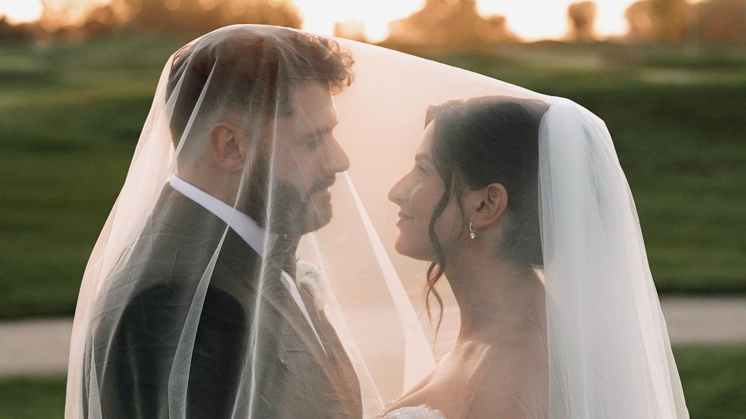 Romantic sunset silhouette of wedding couple with flowing veil.