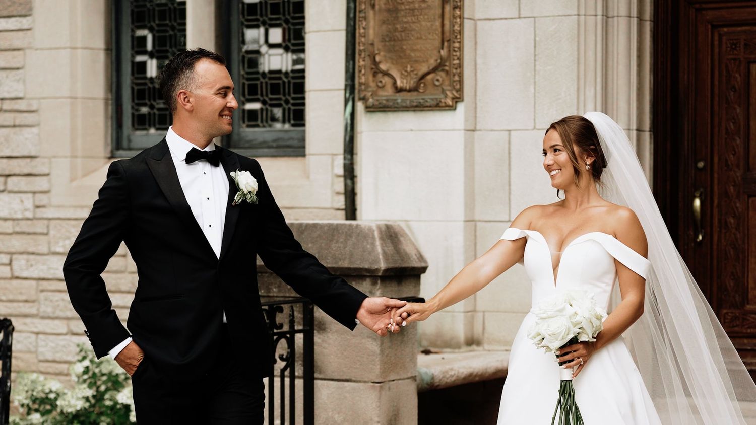 Elegant wedding couple dancing and twirling outside a classic stone building.