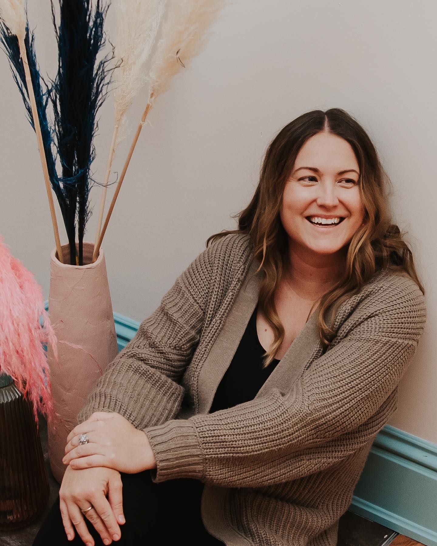 Candid indoor portraits showing joyful expressions while wearing a cozy brown cardigan.