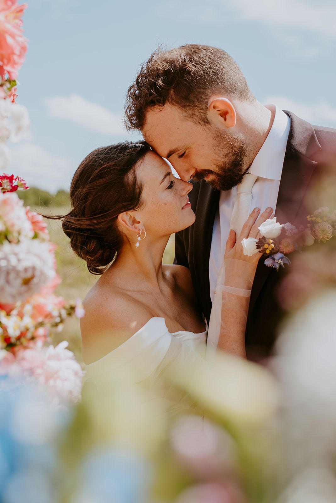Romantic wedding photo series showing close-up kisses with pink flowers in foreground.