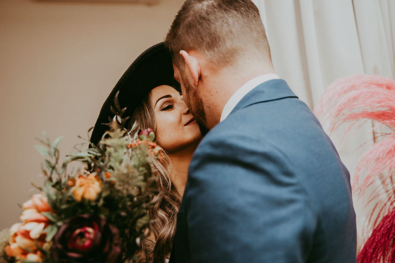 A bride and groom share an intimate moment, with the bride holding a colorful bouquet during their wedding day.