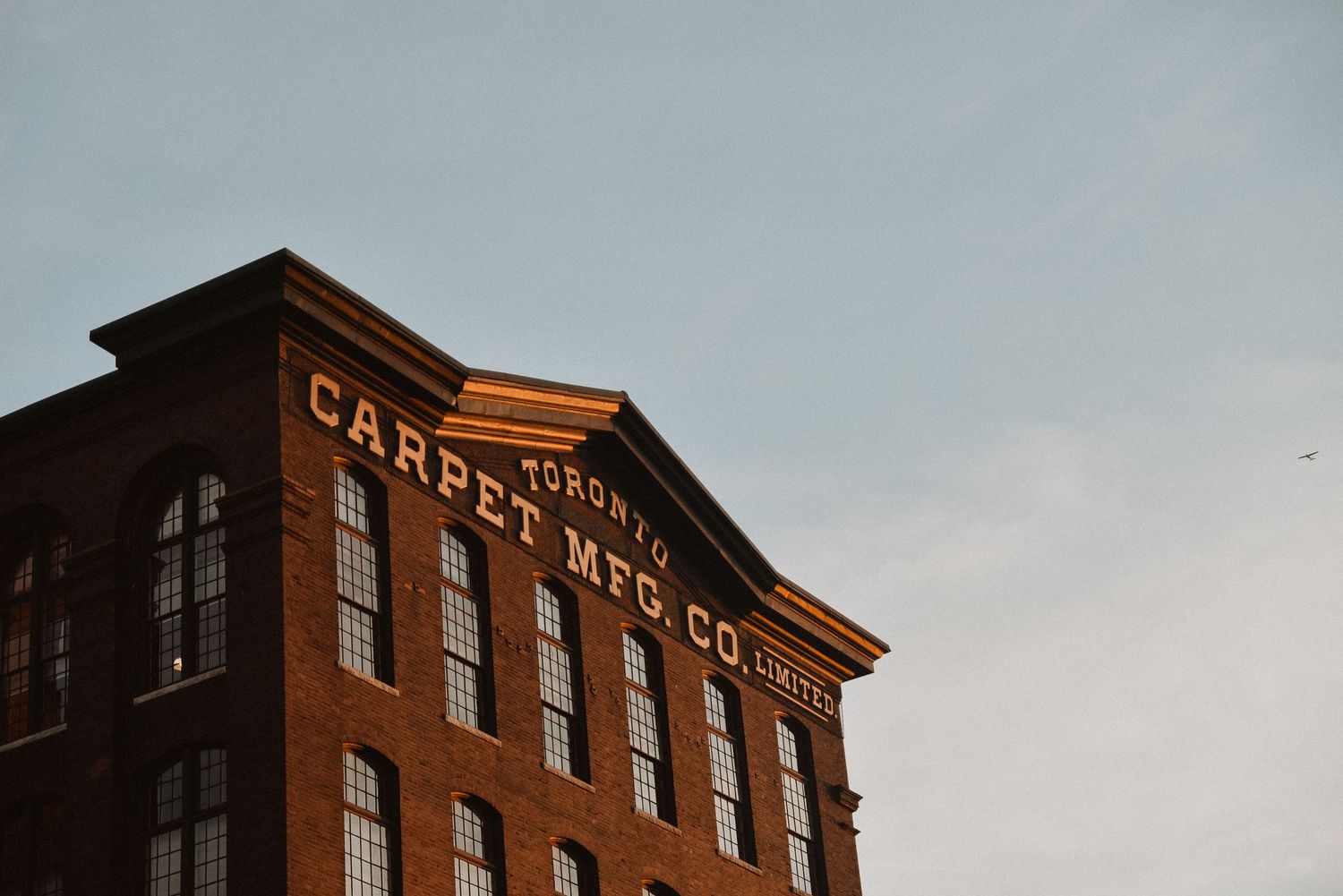 Historic Toronto Carpet Mfg. Co. brick building exterior with vintage signage against a clear sky.