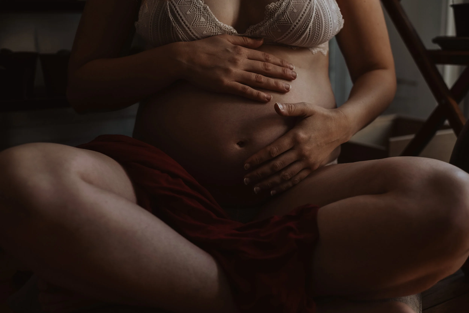 Close-up of pregnant woman's belly with hands gently resting on it.