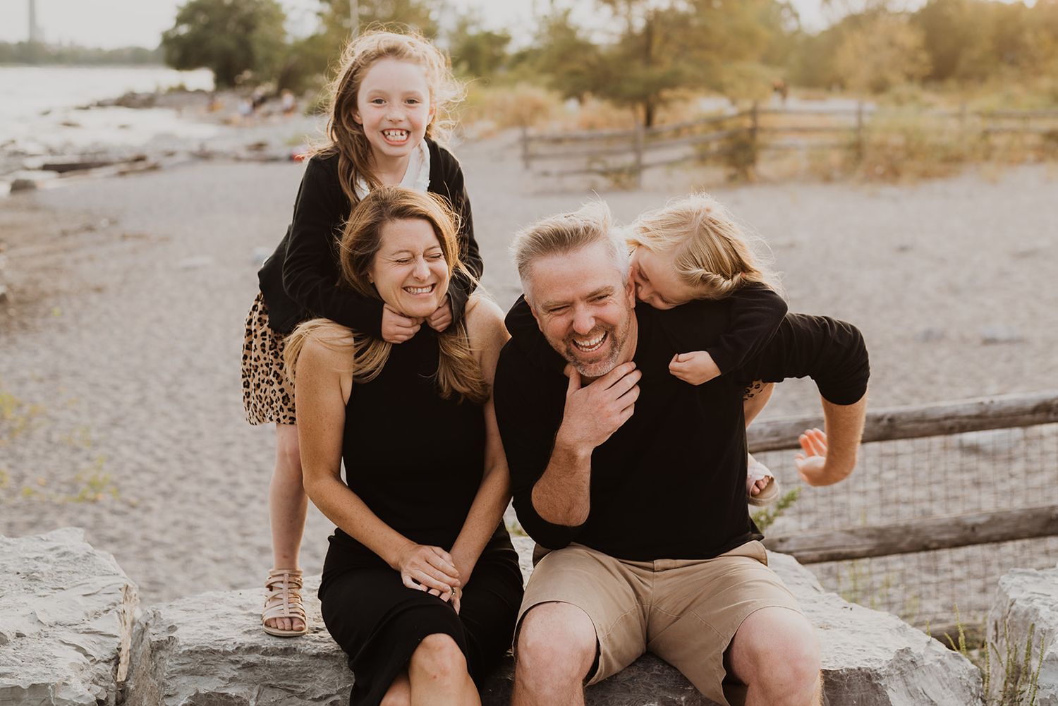 Happy family laughing together while sitting on rocks outdoors.