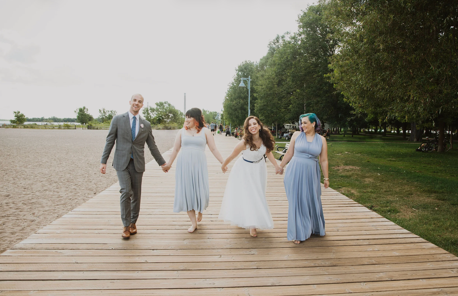 Wedding party walking on boardwalk, bride in blue tulle dress with groom and bridesmaids in matching blue gowns.