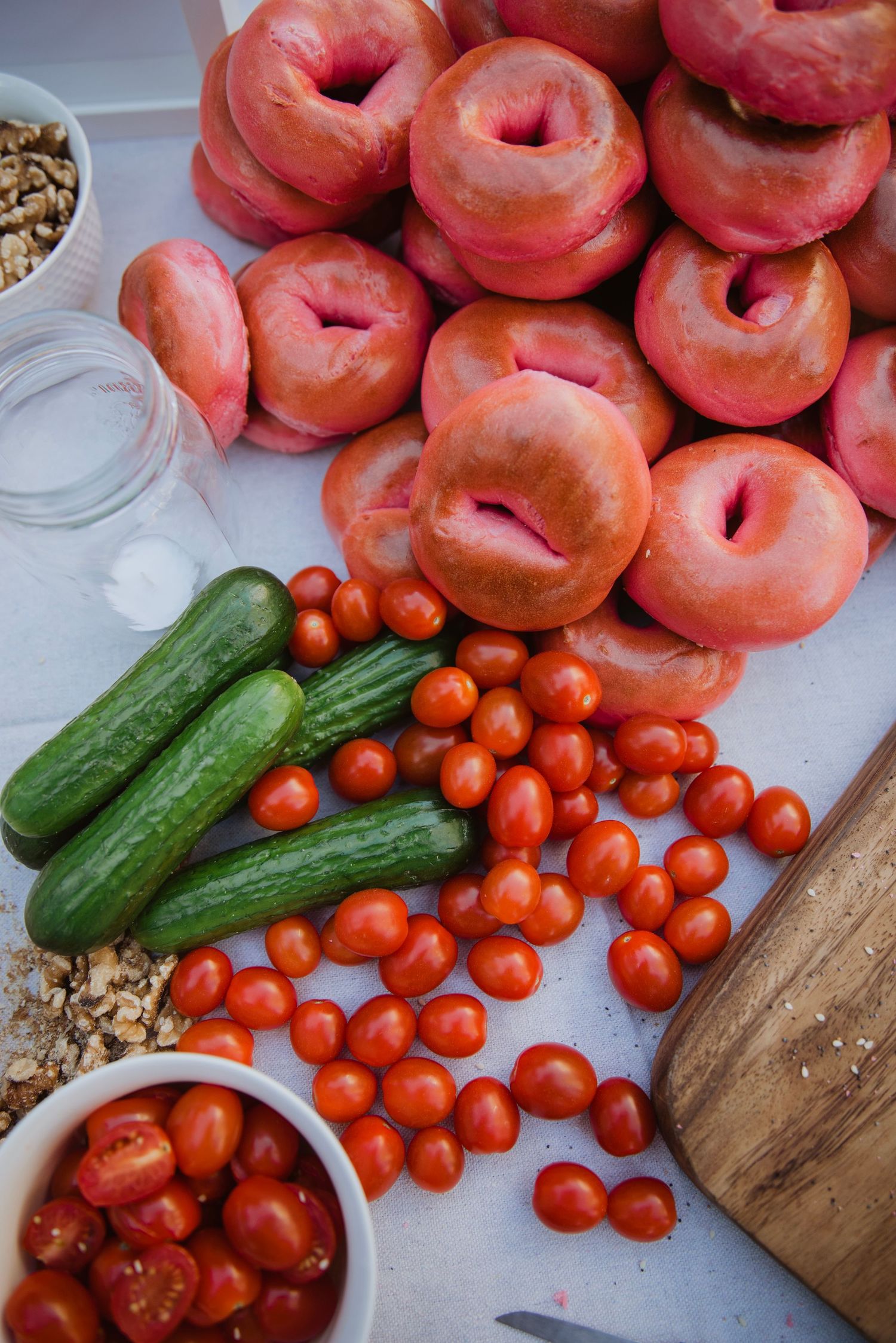Fresh cherry tomatoes, cucumbers, and peeled peaches arranged on a white surface with a wooden cutting board.