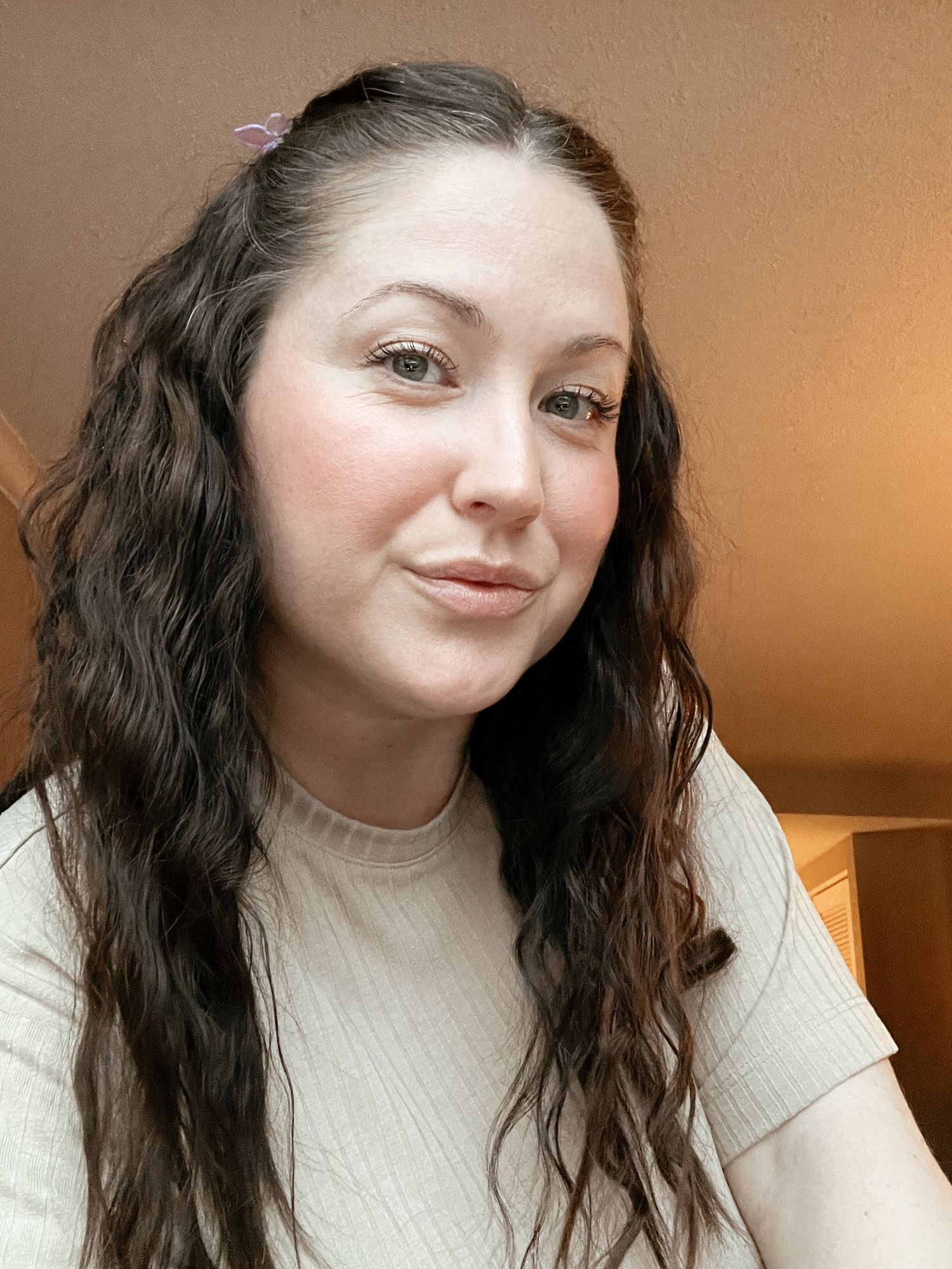 Close-up selfie portraits showing warm expressions and long dark wavy hair against a neutral background.