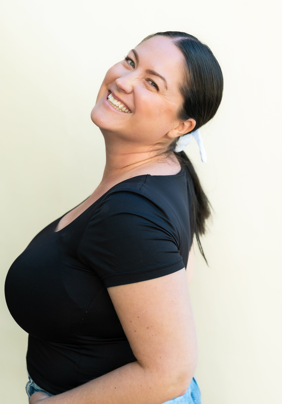 Portrait of woman in black shirt smiling against light background.