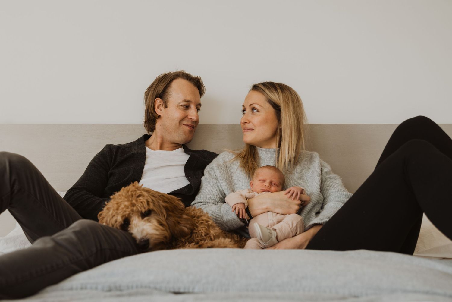 Lifestyle family photo series with newborn baby and pet dog relaxing at home.