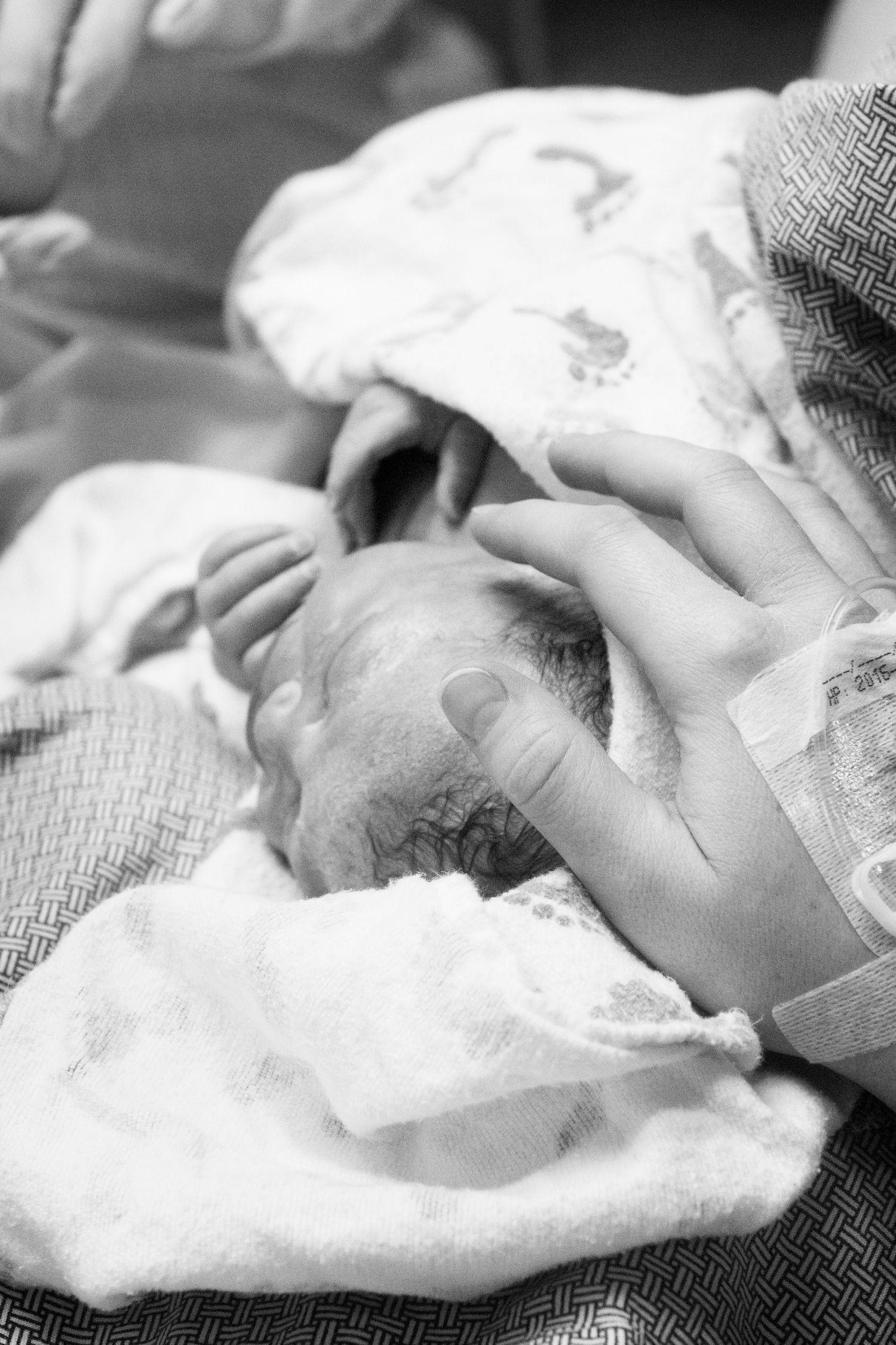 mother gently touching her newborn baby after birth