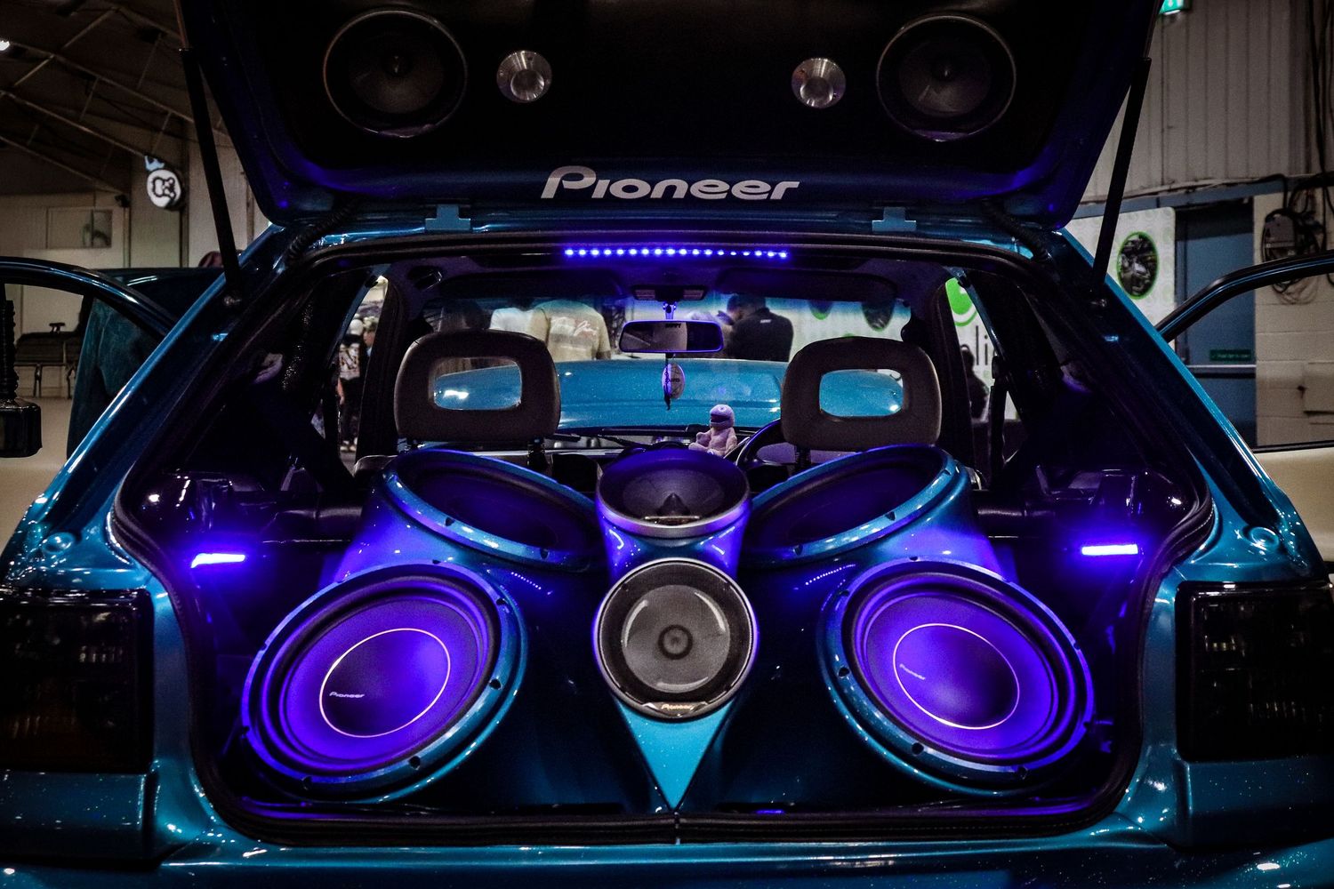 Custom car trunk with Pioneer subwoofers and purple LED lighting system on display.