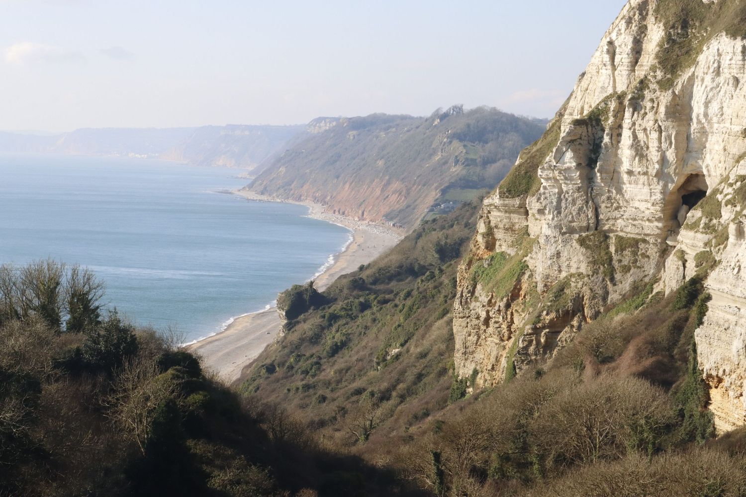 Scenic coastal cliffs with green hills and blue sea.