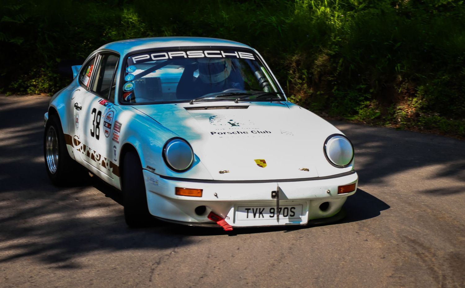 White Porsche 911 RSR race car number 38 on a forest road.
