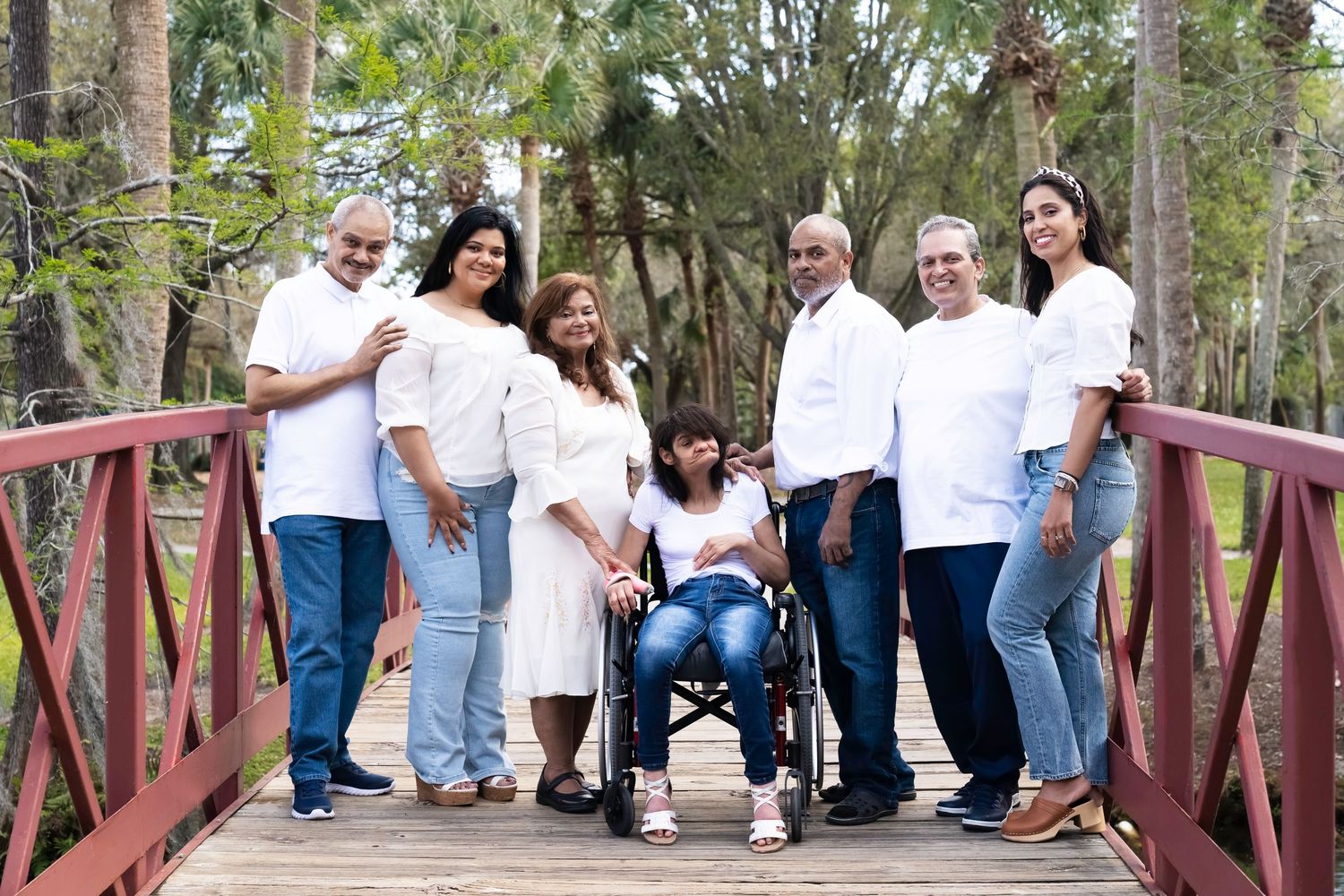 Outdoor family photograph of a family on a bridge wearing white shirts and blue jeans.