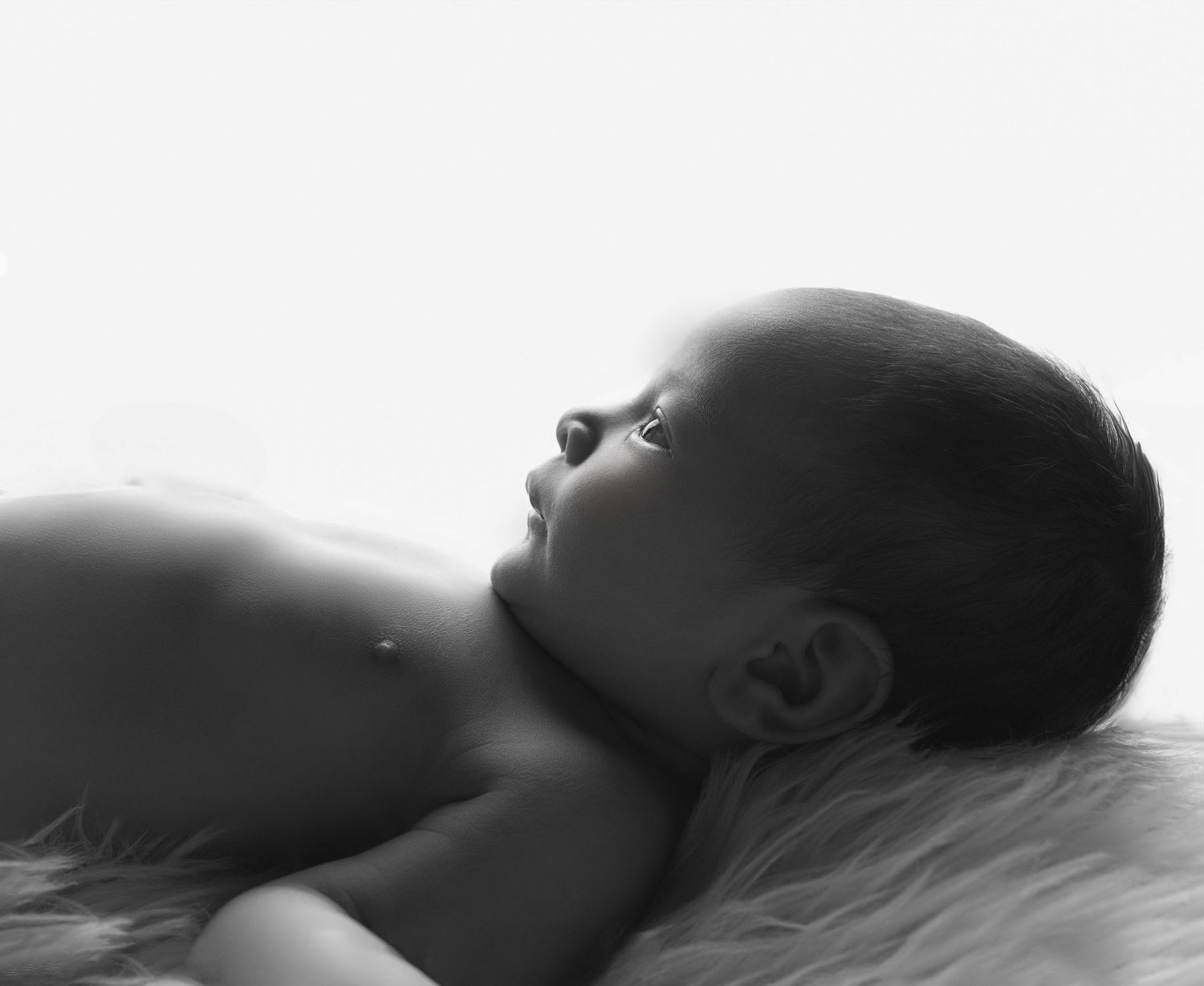 Artistic black and white photo of a person floating in water with eyes closed in a serene pose.