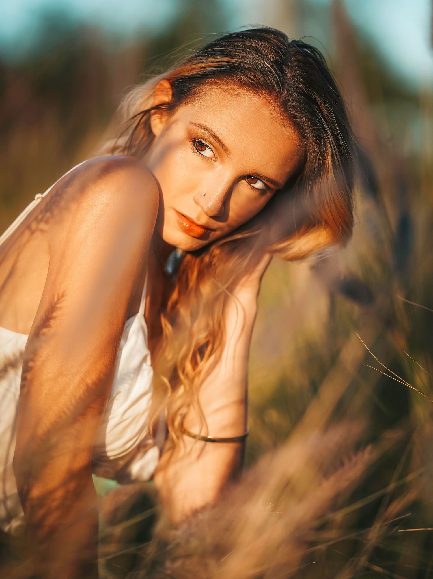 A portrait of a woman looking back towards the sun in a field in natural setting with golden hour lighting.