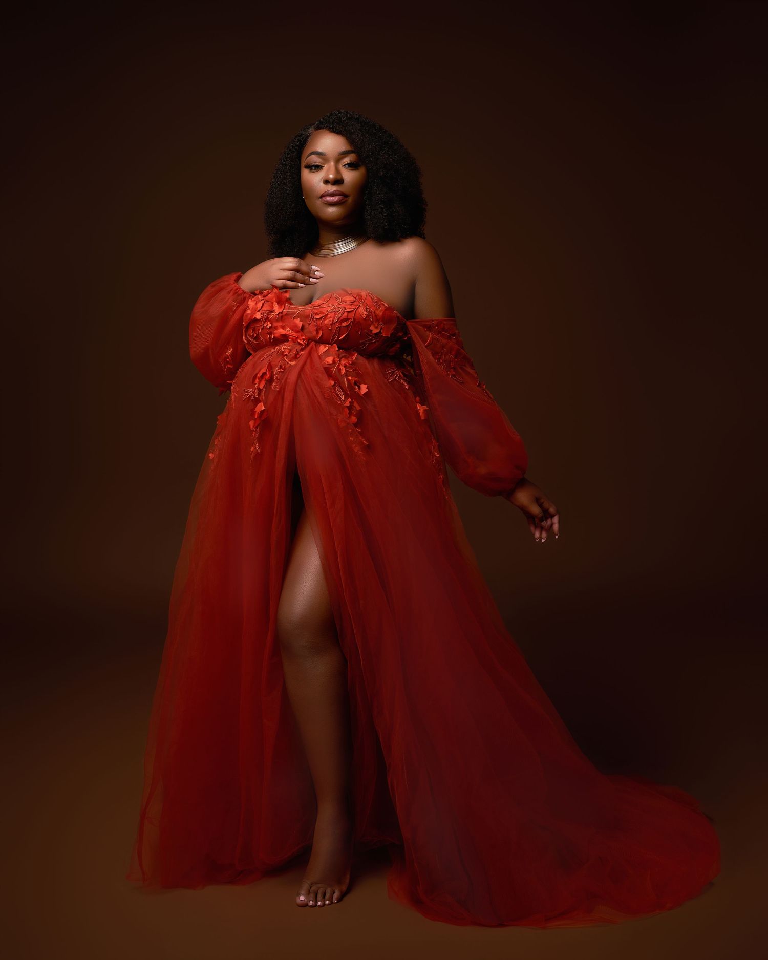 Artistic maternity photoshoot featuring flowing red fabric against a dark background.