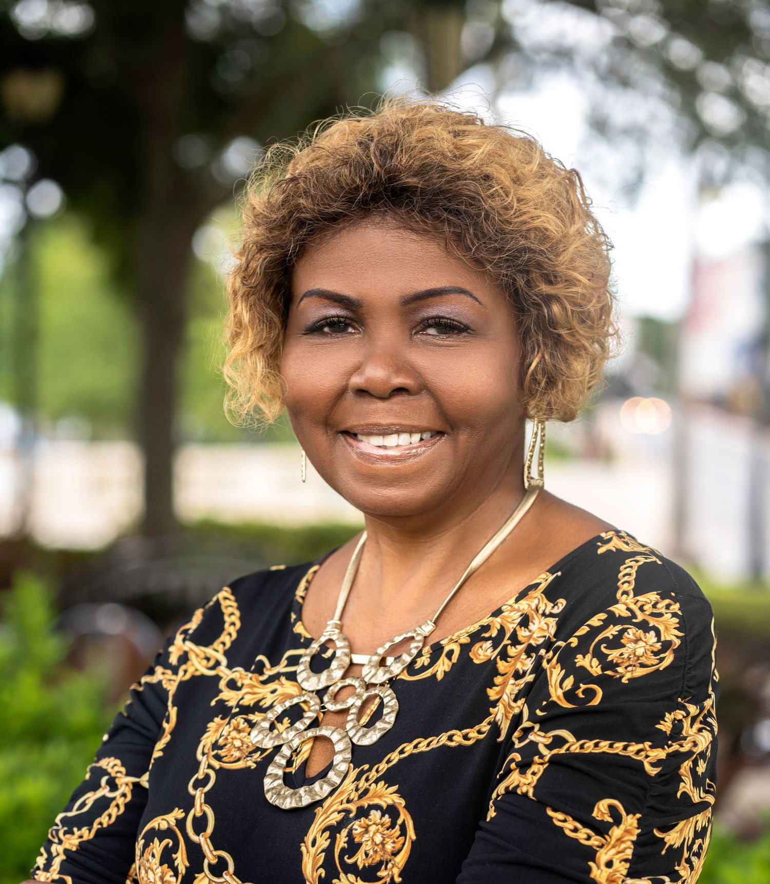Outdoor portraits of a woman wearing a black and gold patterned outfit.