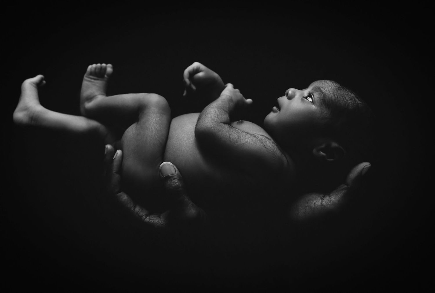 Black and white artistic portrait of a sleeping newborn baby in dramatic lighting.